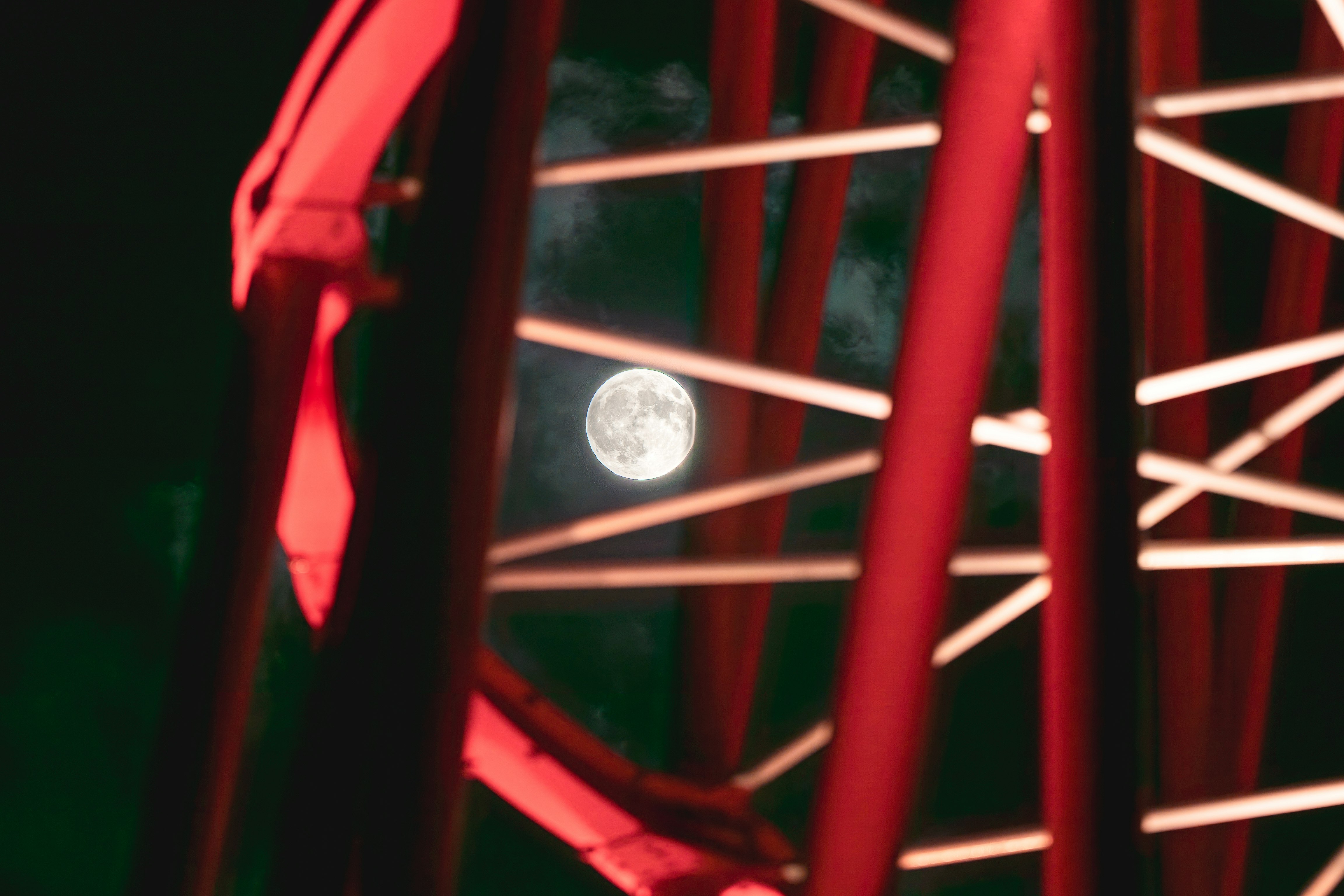 Bulan terlihat di sela jeruji logam merah pada malam hari