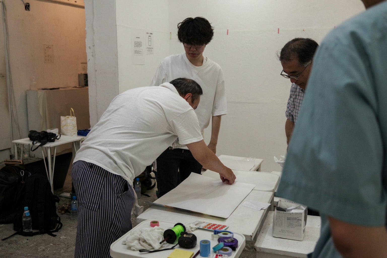 Diversi uomini che lavorano a un tavolo in una stanza con pareti bianche concentrandosi sulla creazione artistica