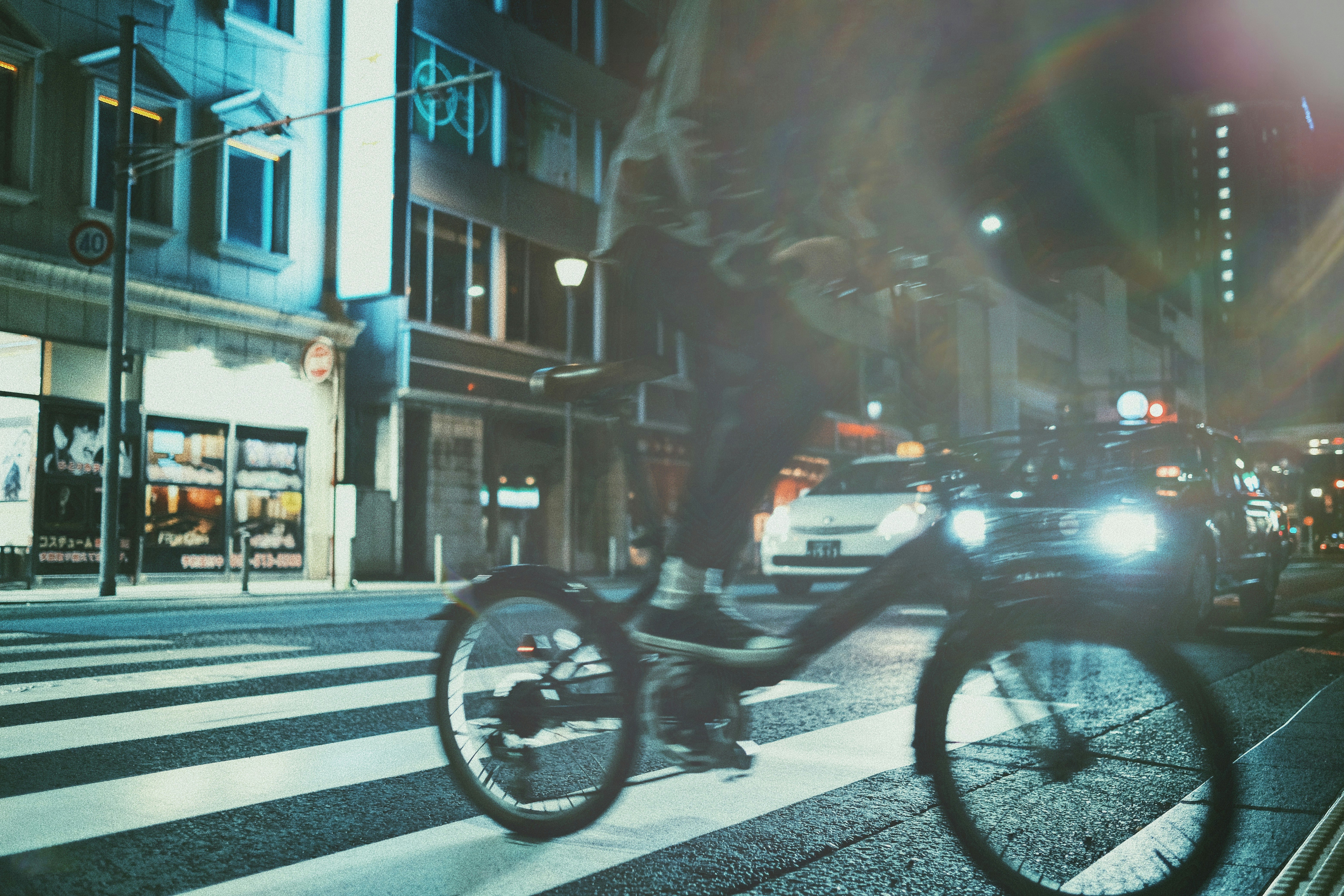 strada urbana notturna con attraversamento pedonale e biciclette
