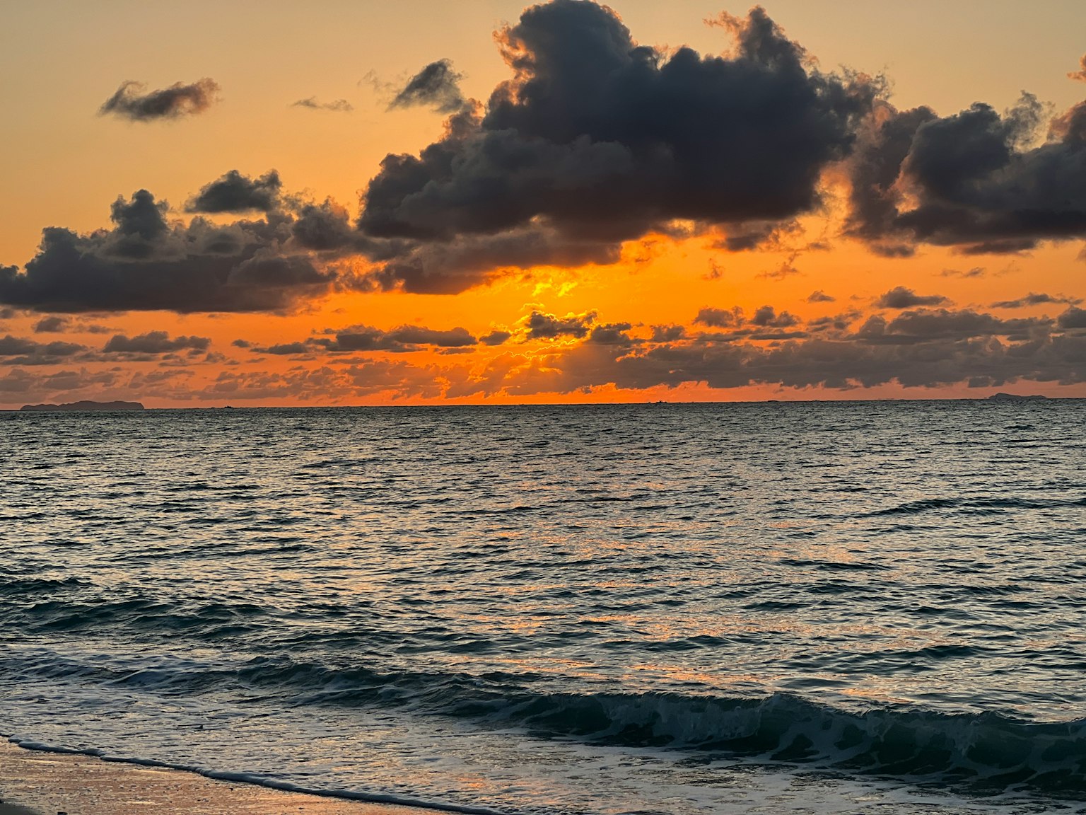 Vista panoramica dell'oceano al tramonto con cielo arancione vivace e nuvole