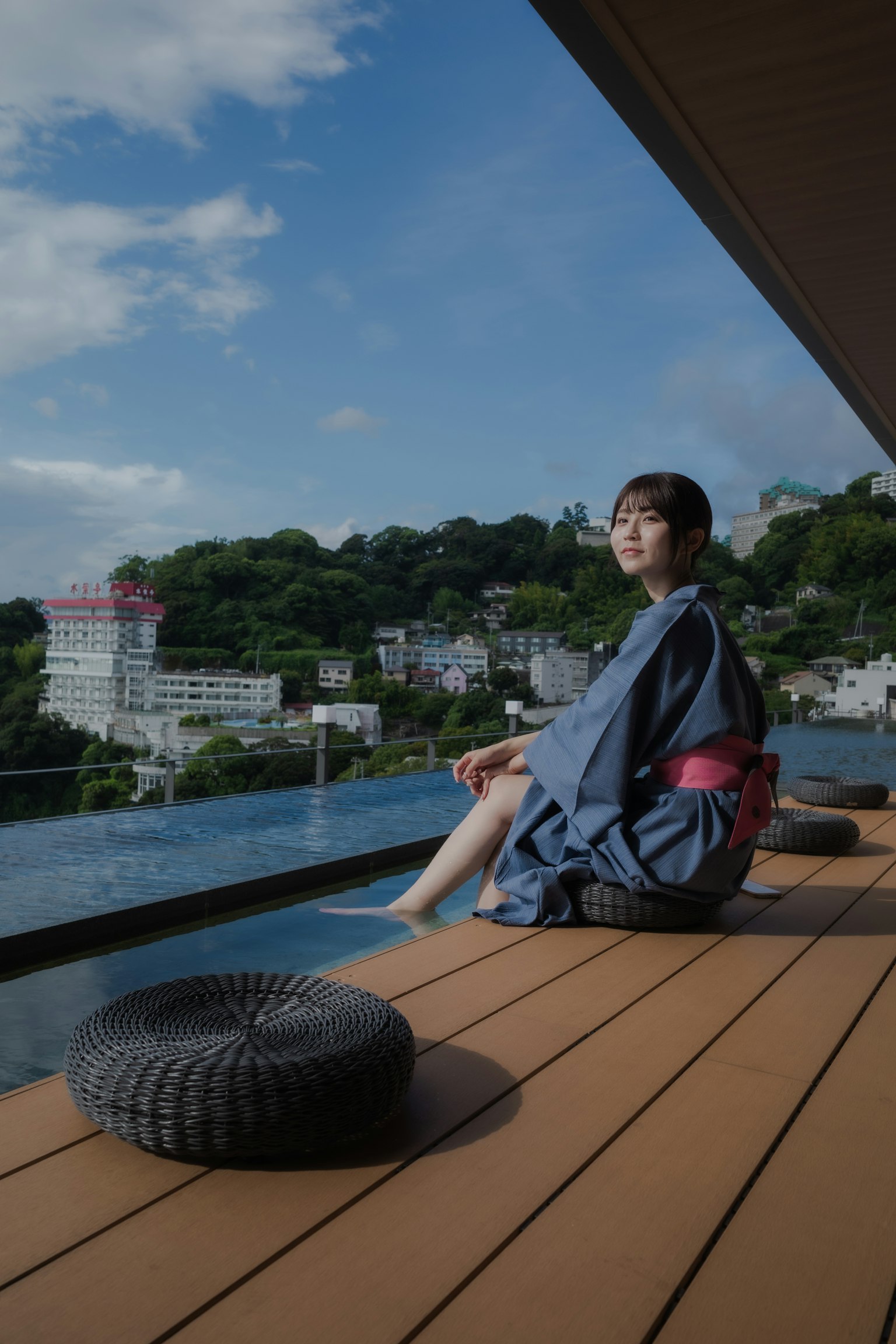 경치 좋은 전망을 배경으로 나무 데크에 앉아 있는 기모노를 입은 여성