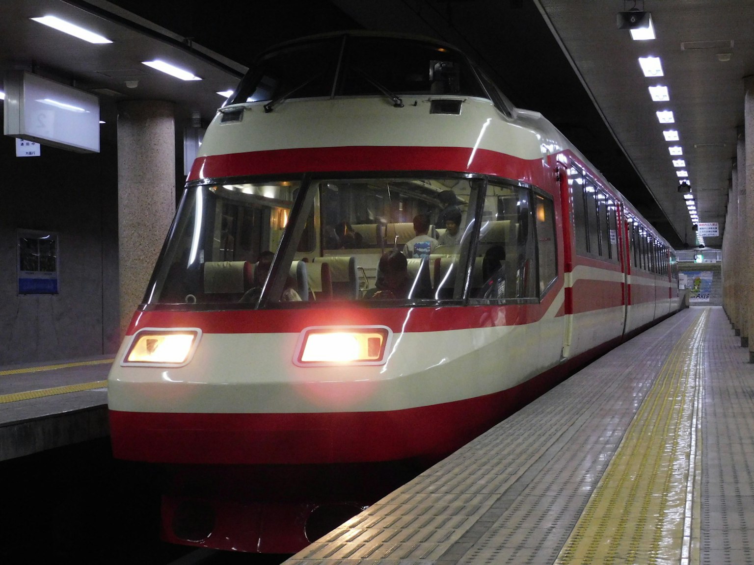 Kereta merah dan putih berhenti di platform stasiun