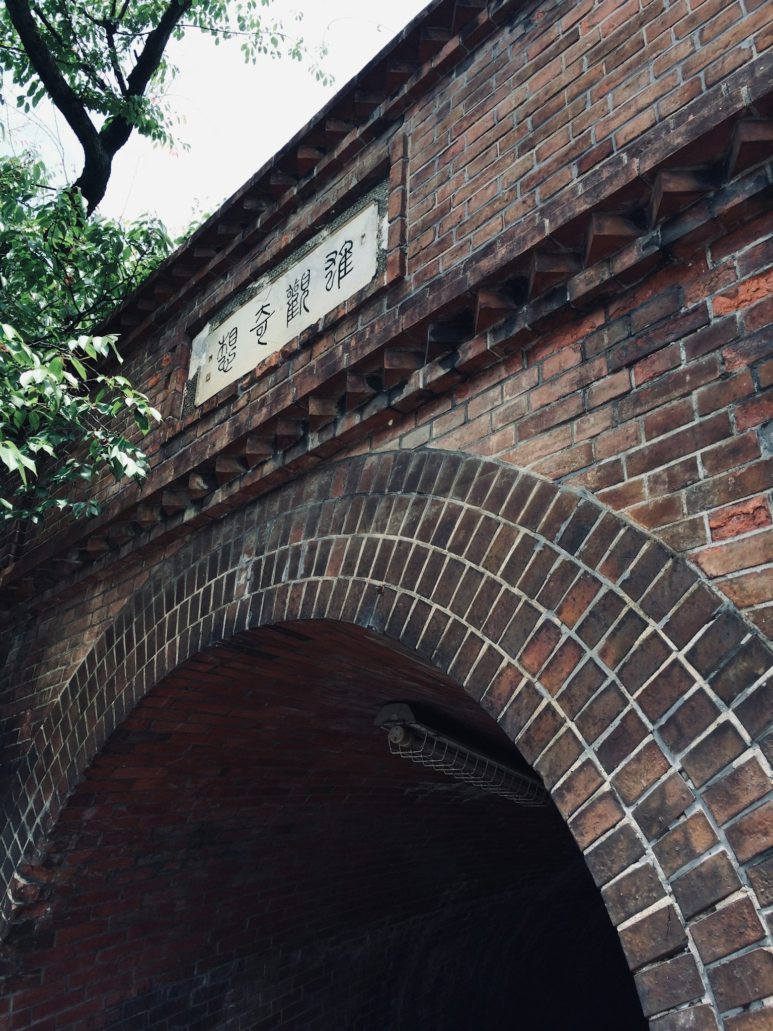 Edificio storico con arco in mattoni e alberi circostanti