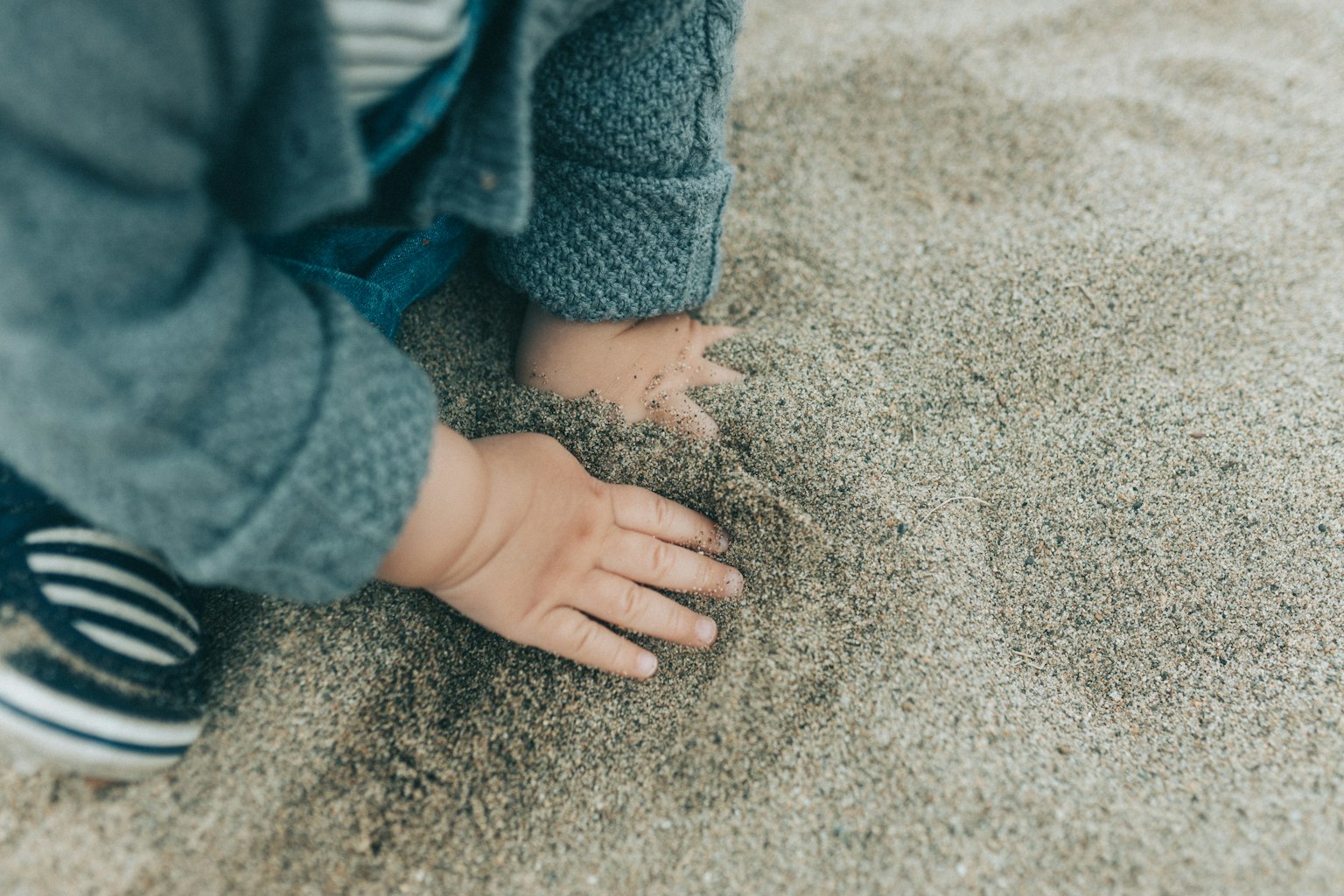 Child's hands playing in the sand