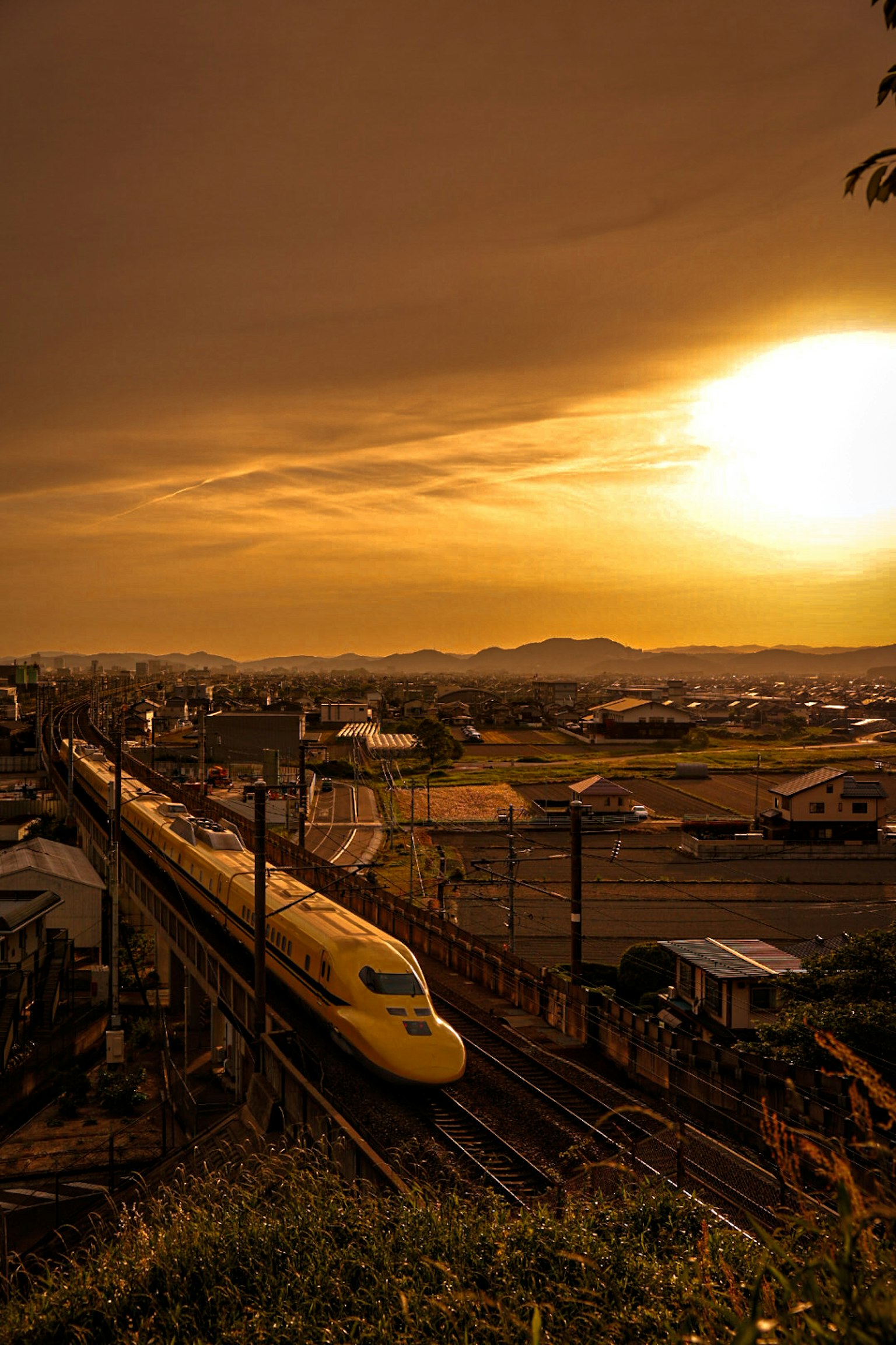 รถไฟชินคันเซนสีเหลืองวิ่งท่ามกลางท้องฟ้ายามพระอาทิตย์ตก