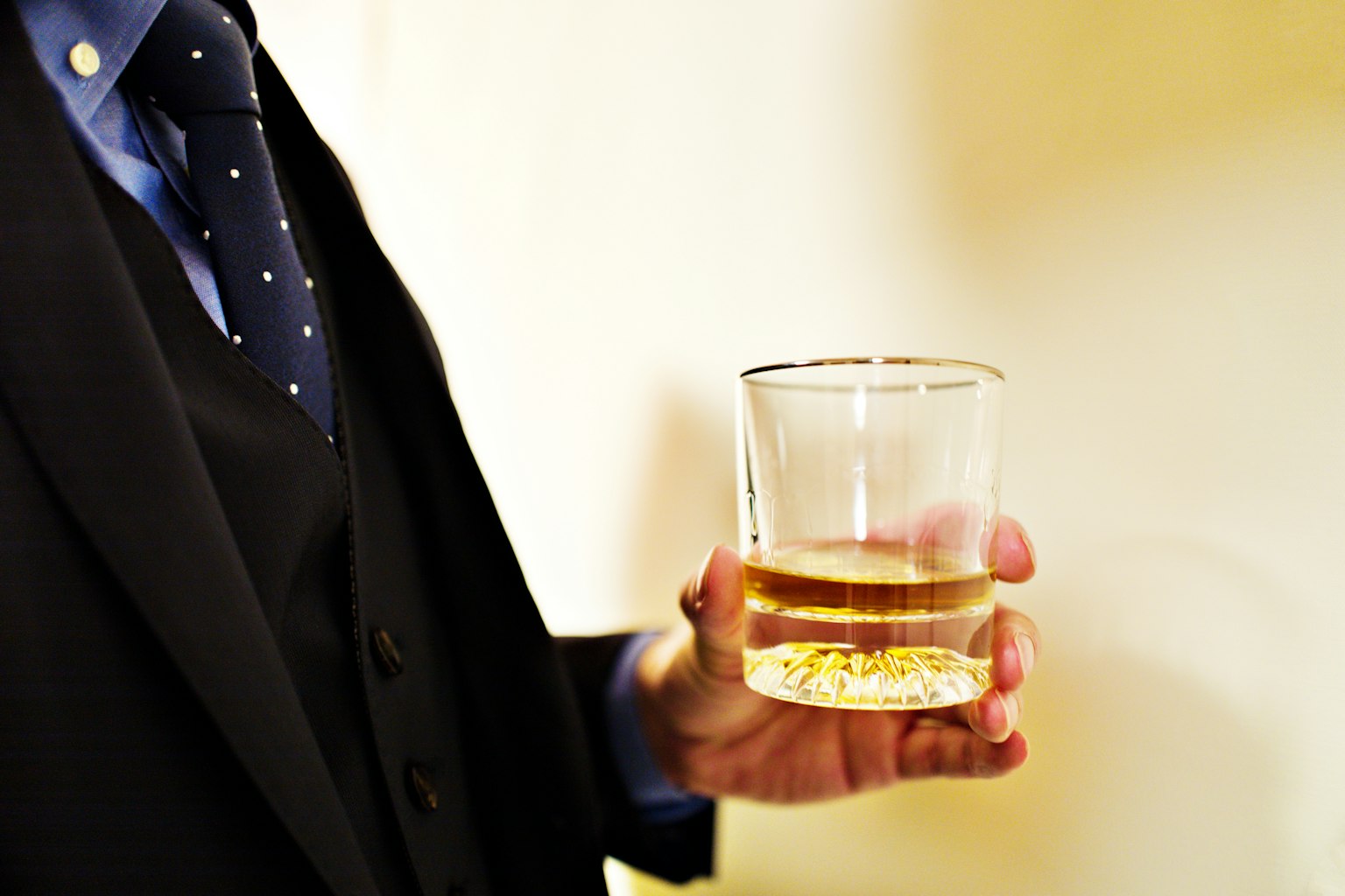 Un hombre con traje sosteniendo un vaso de whisky