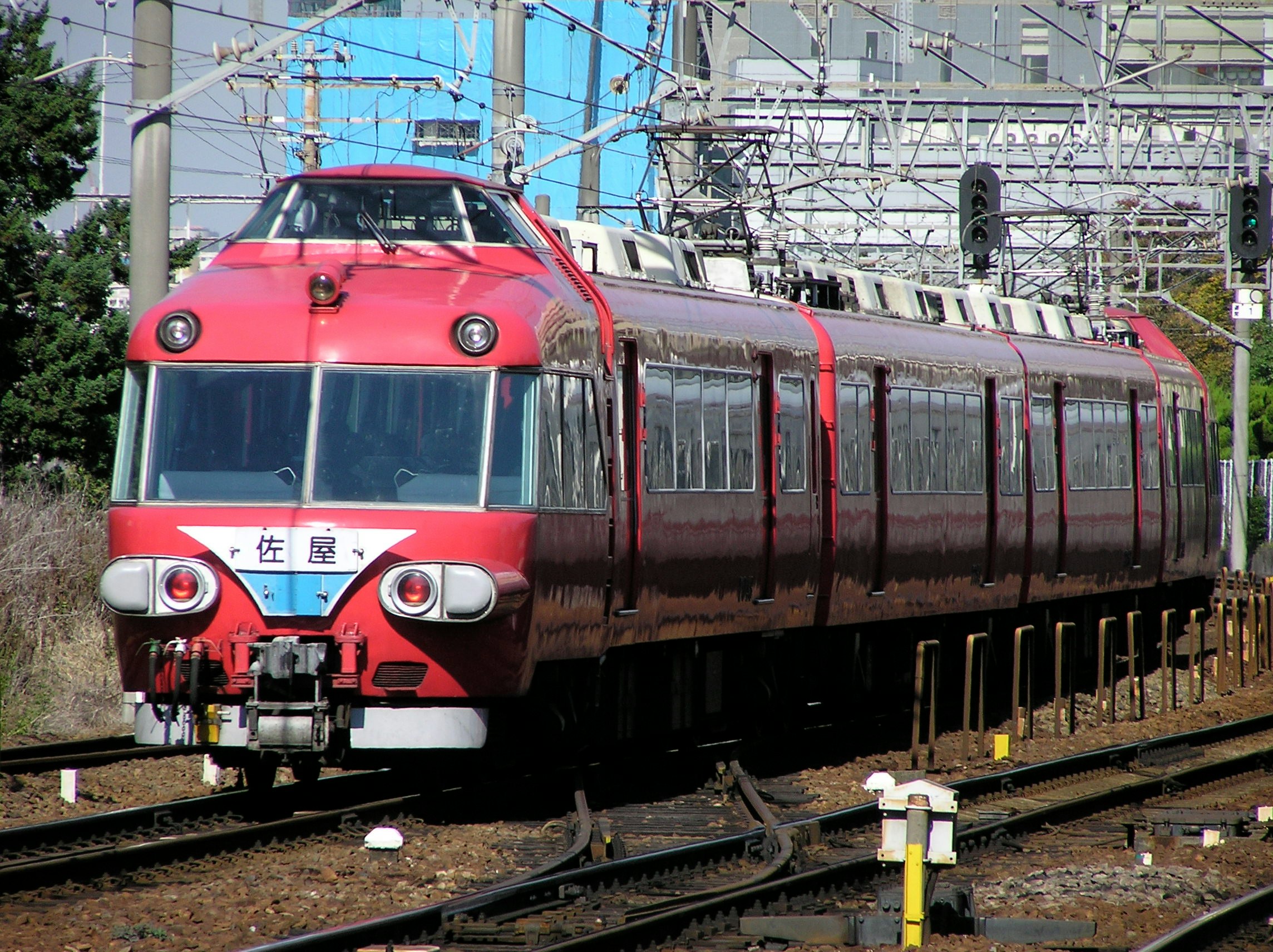 赤い電車が線路上を走る駅のホーム前景