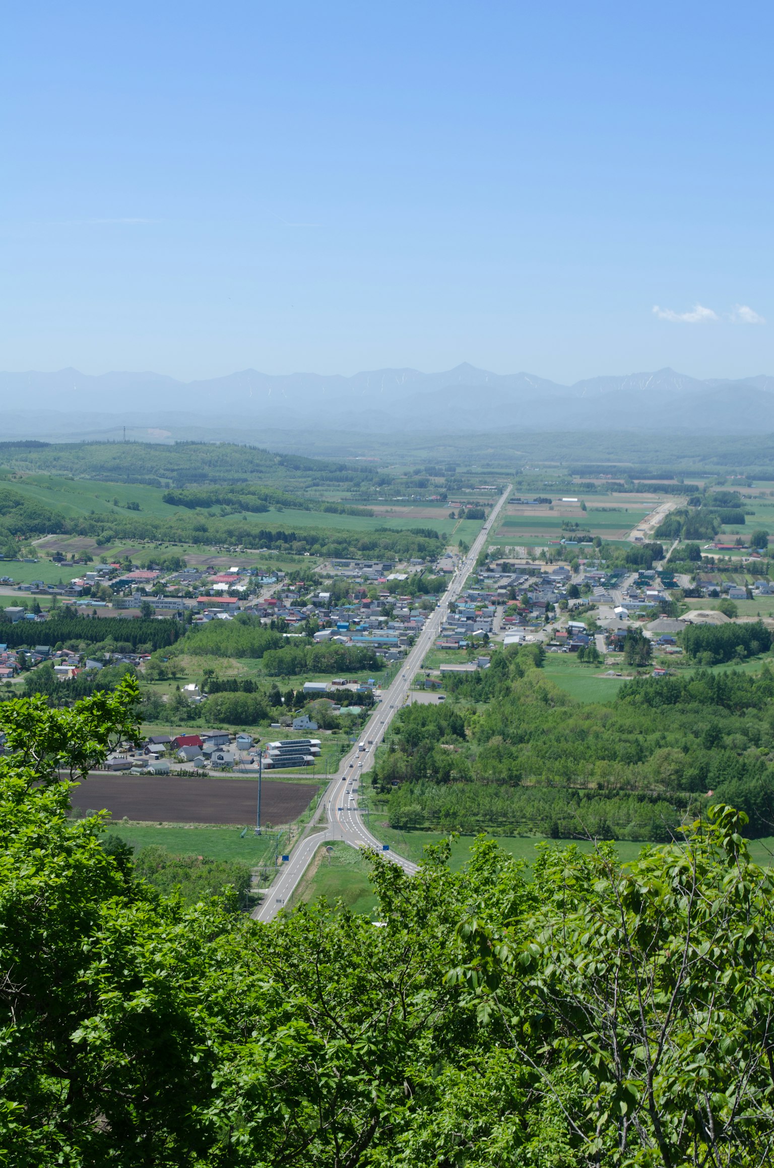 Ein Panoramablick auf eine Stadt, umgeben von üppigem Grün und fernen Bergen