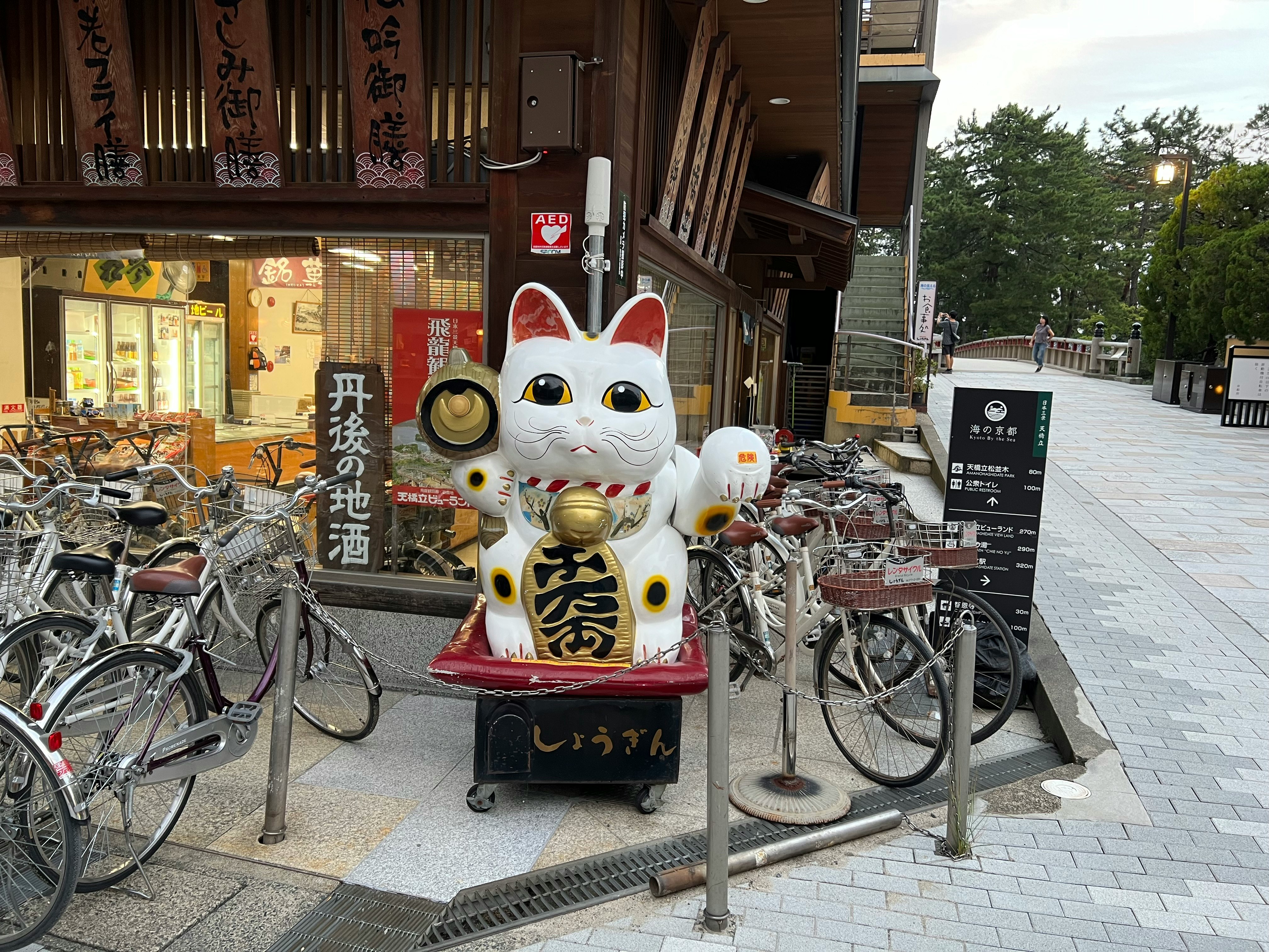 Patung maneki-neko dan deretan sepeda di depan toko