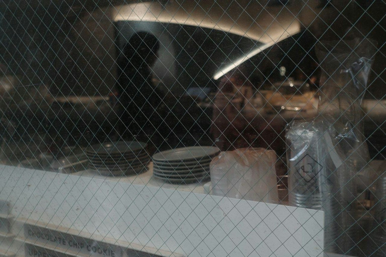 透過窗戶看到的餐廳廚房內部，有盤子和烹飪用具可見