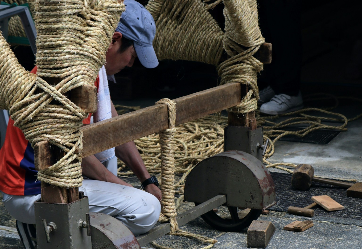 Mann arbeitet in der Nähe einer von Seilen gestützten Holzstruktur
