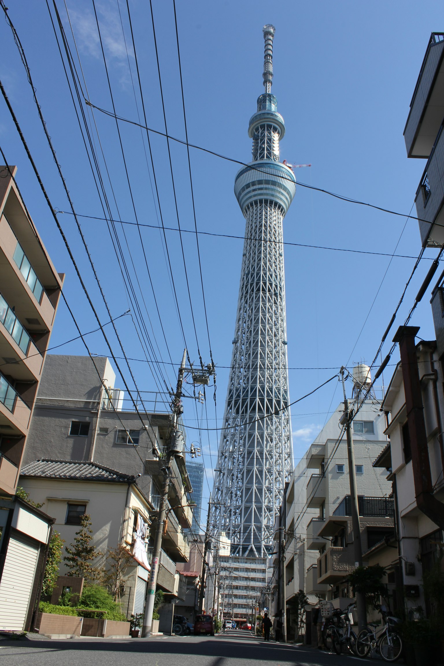 Tokyo Skytree che svetta su una strada sotto un cielo blu chiaro