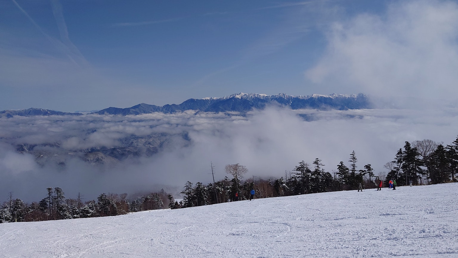 Verschneite Landschaft mit Bergen, die durch Wolken sichtbar sind