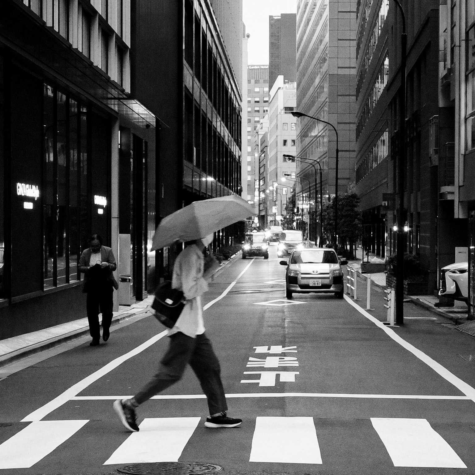 Seorang pebisnis menyeberang jalan dengan payung di pemandangan kota