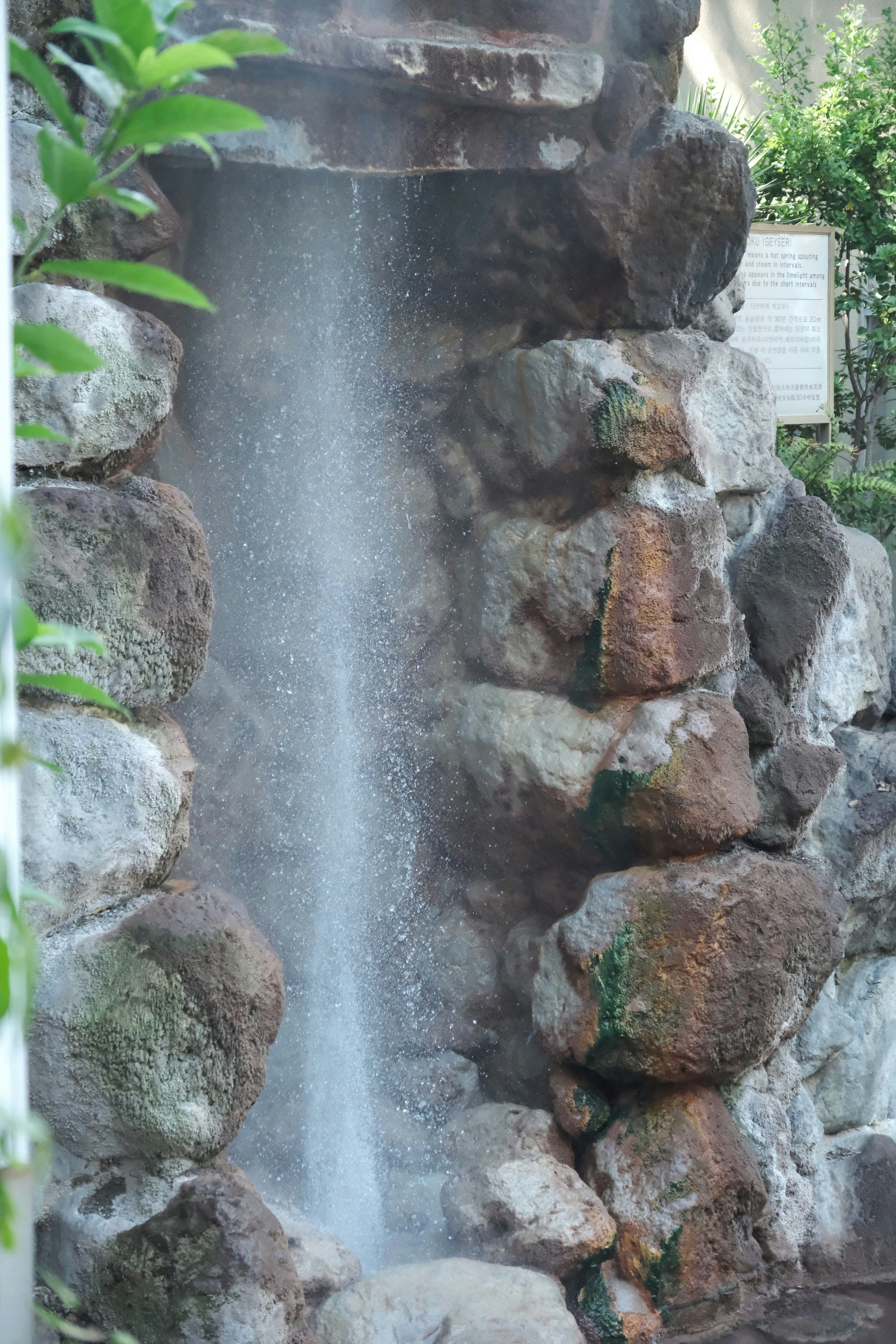 岩壁から流れ落ちる滝の湯けむりのある景観