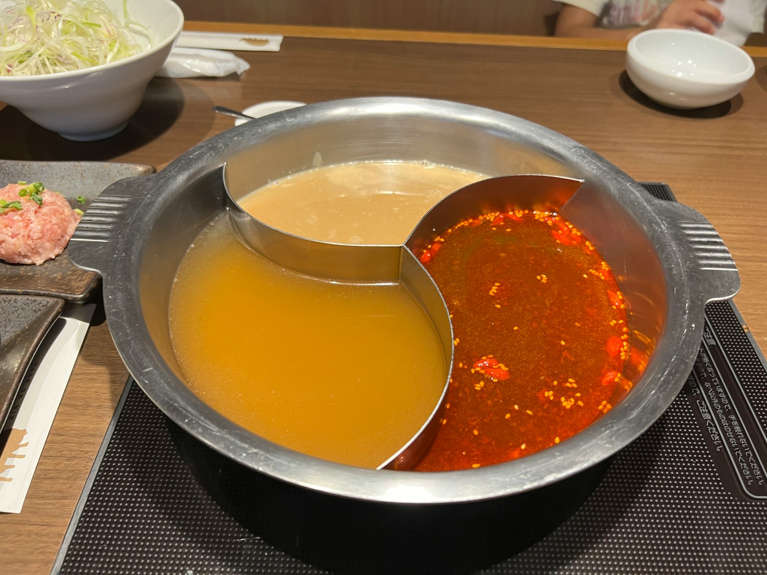 A hot pot with two sections of broth one spicy and one mild