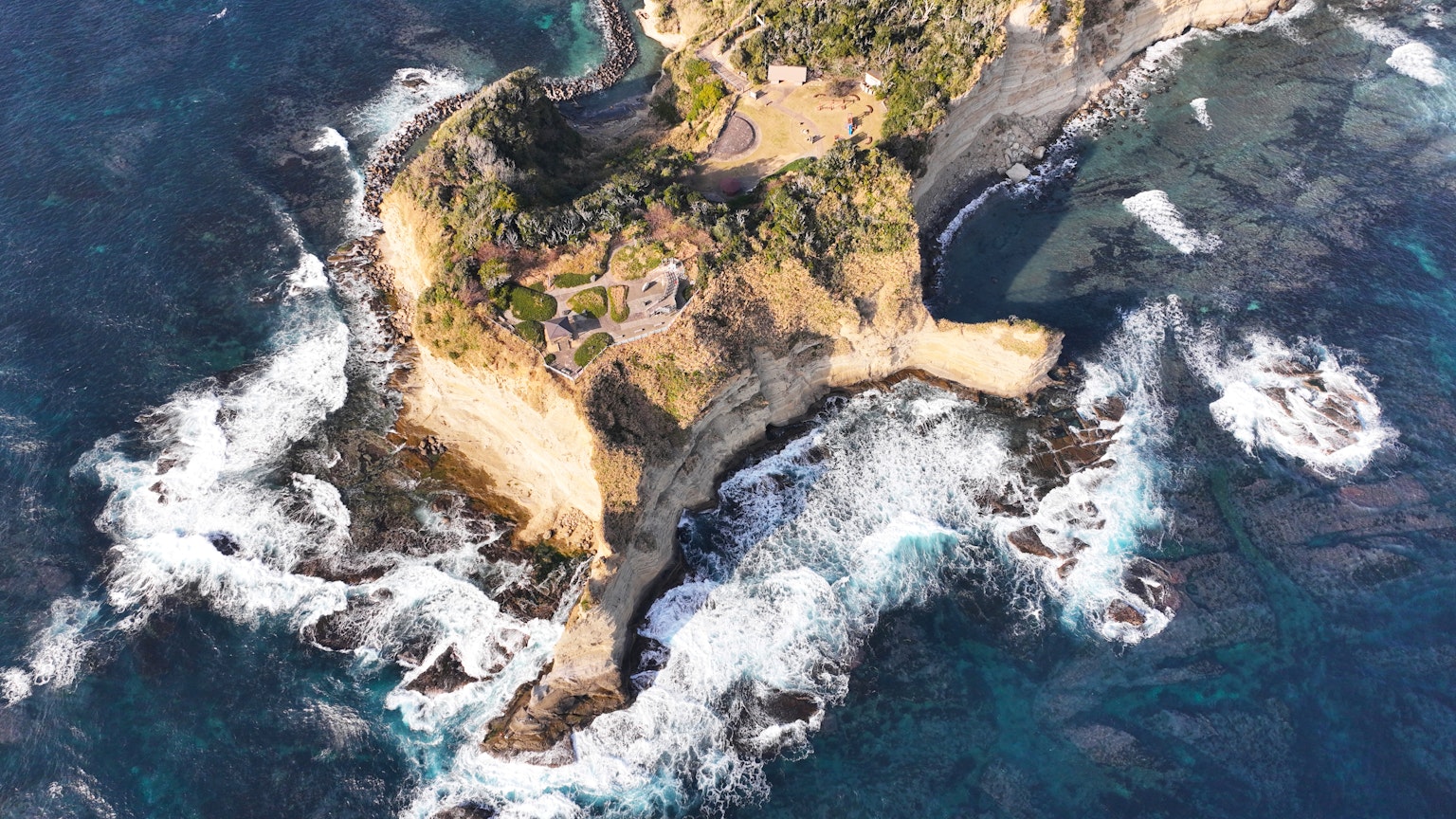 Vista aerea di un'isola piccola circondata da onde oceaniche che si infrangono sulla riva