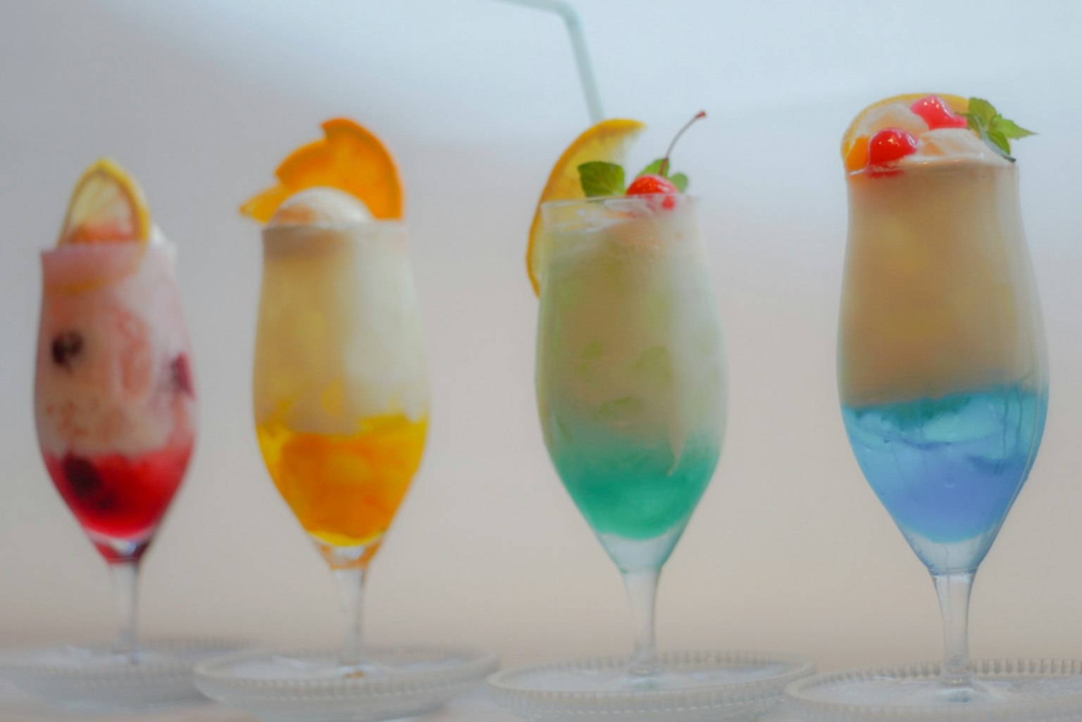 Una fila di bicchieri da cocktail colorati con guarnizioni di frutta