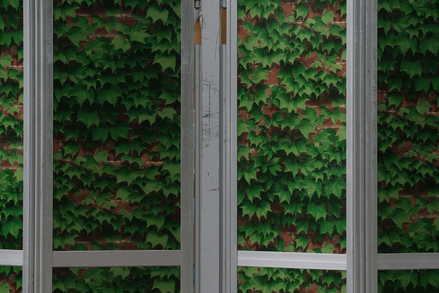 Una pared cubierta de hojas verdes y una estructura de metal