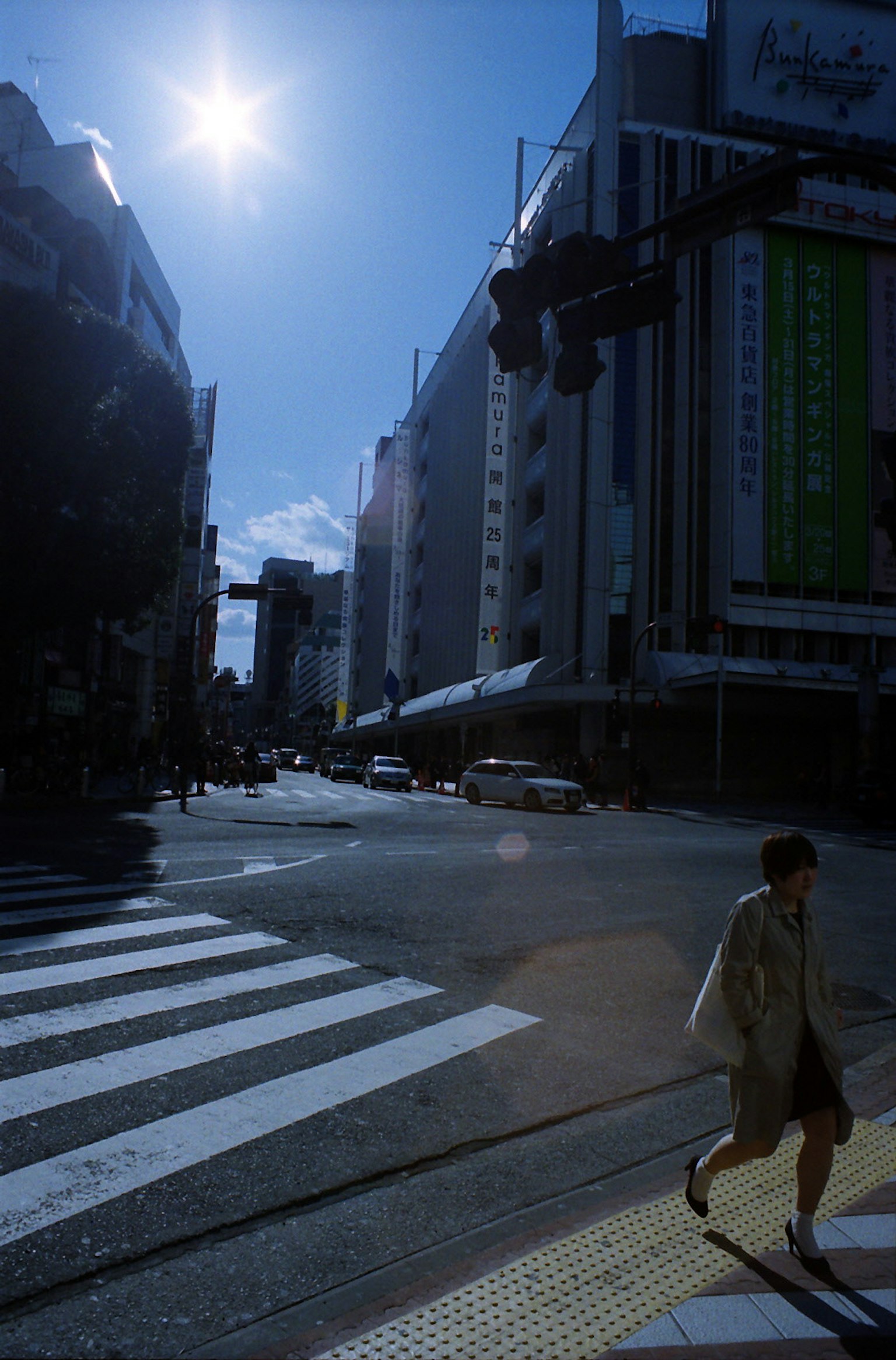 Cityscape with a person crossing the street under a blue sky and buildings in the background