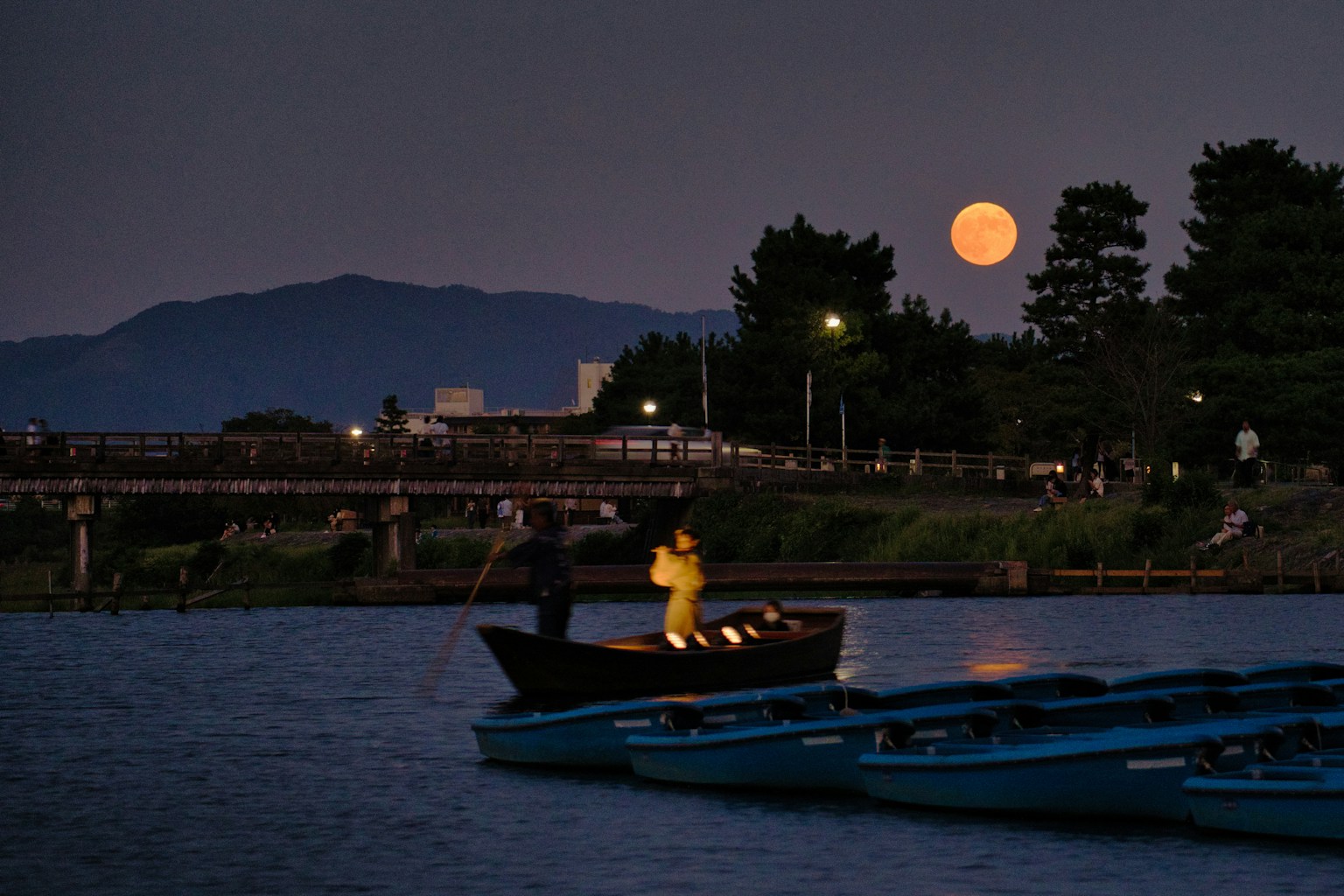 Pemandangan indah perahu kecil di sungai dengan bulan purnama di malam hari