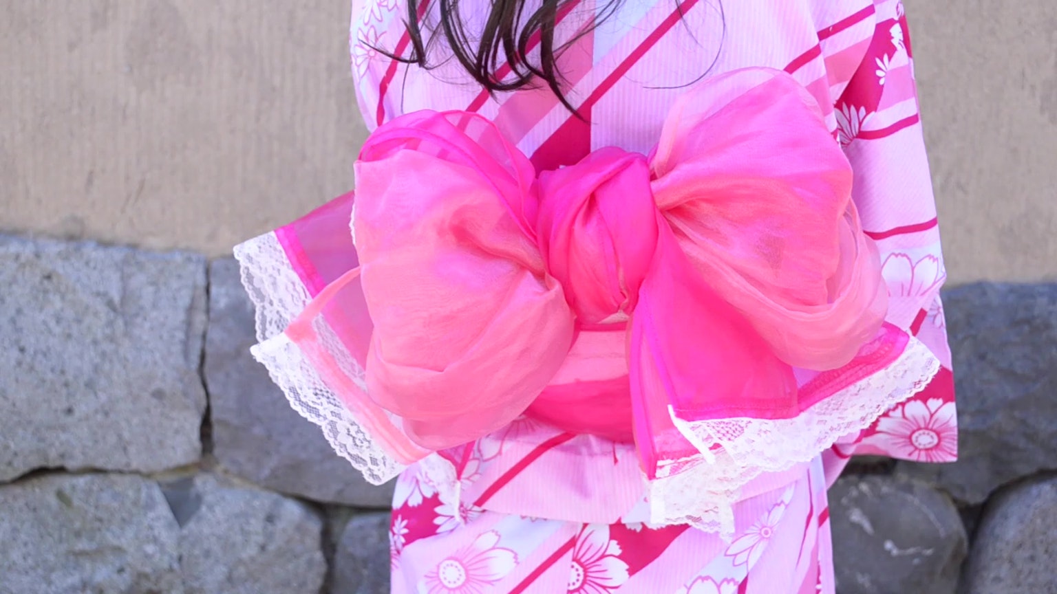 Gadis mengenakan yukata pink cerah dengan pita besar