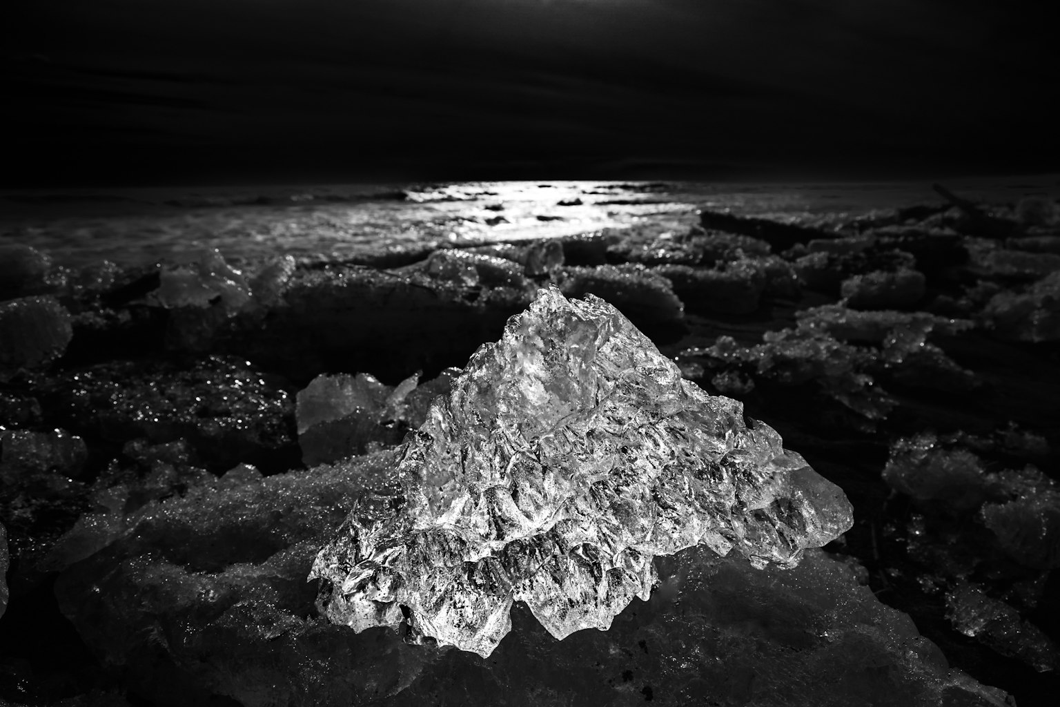 Una formazione di ghiaccio a forma di piramide illuminata dalla luna sopra l'oceano