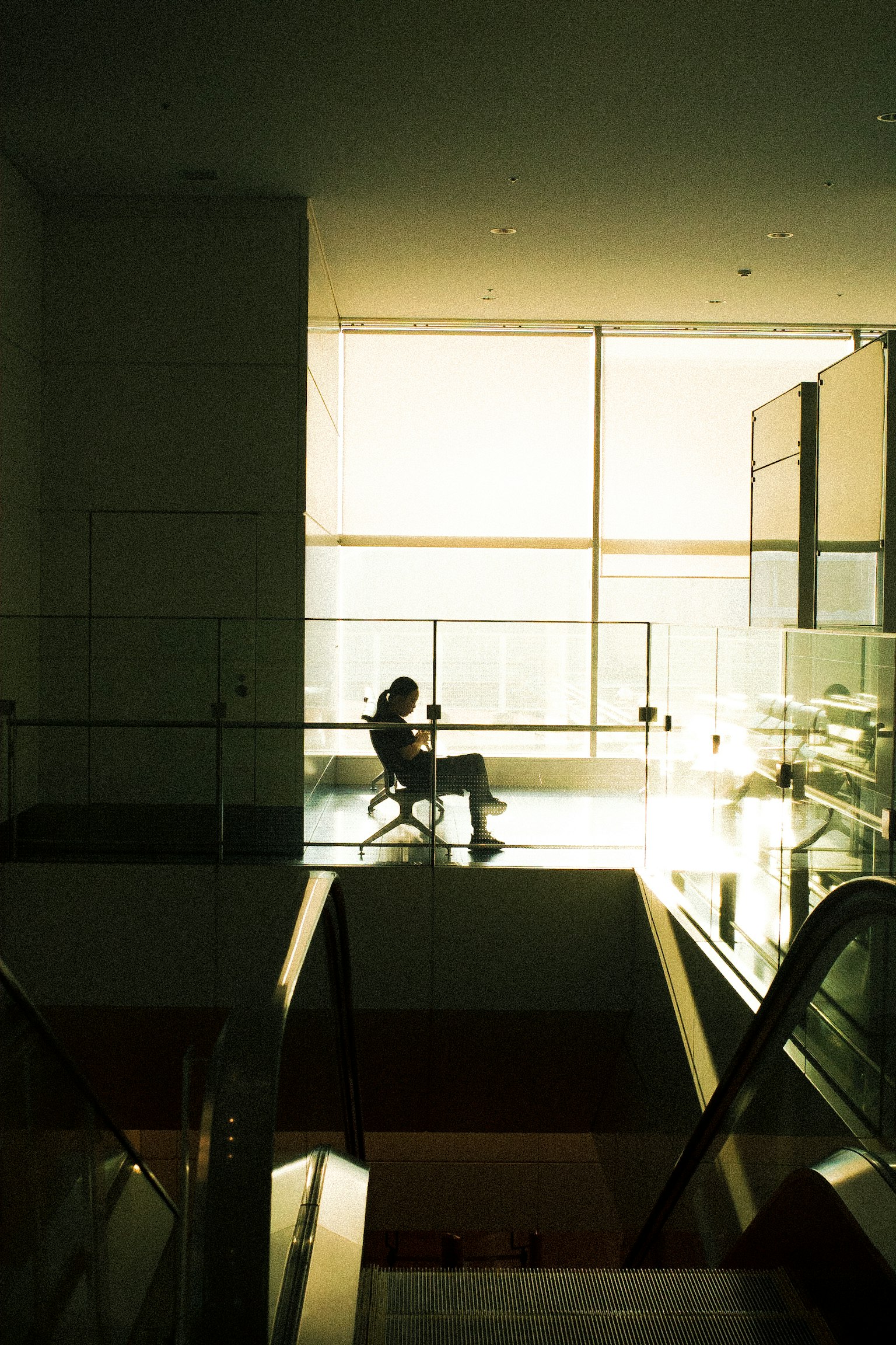 Silhouette einer Person, die an einem hellen Fenster in einem modernen Innenraum sitzt