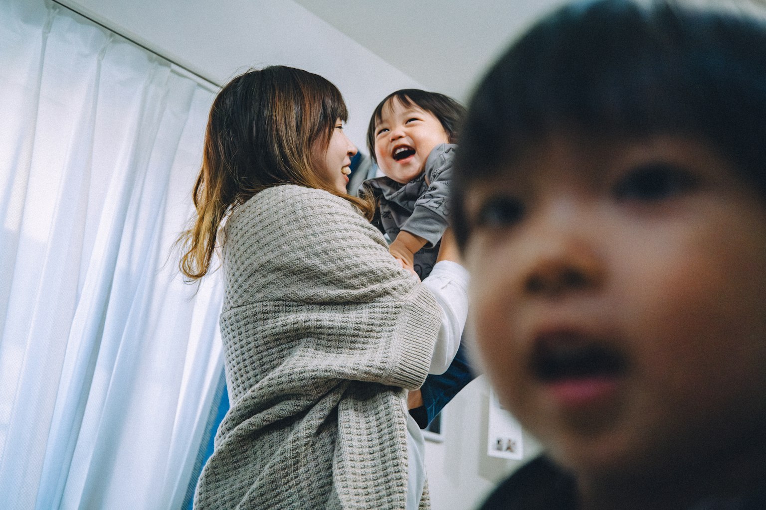 밝은 방에서 웃고 있는 아이를 안고 있는 엄마