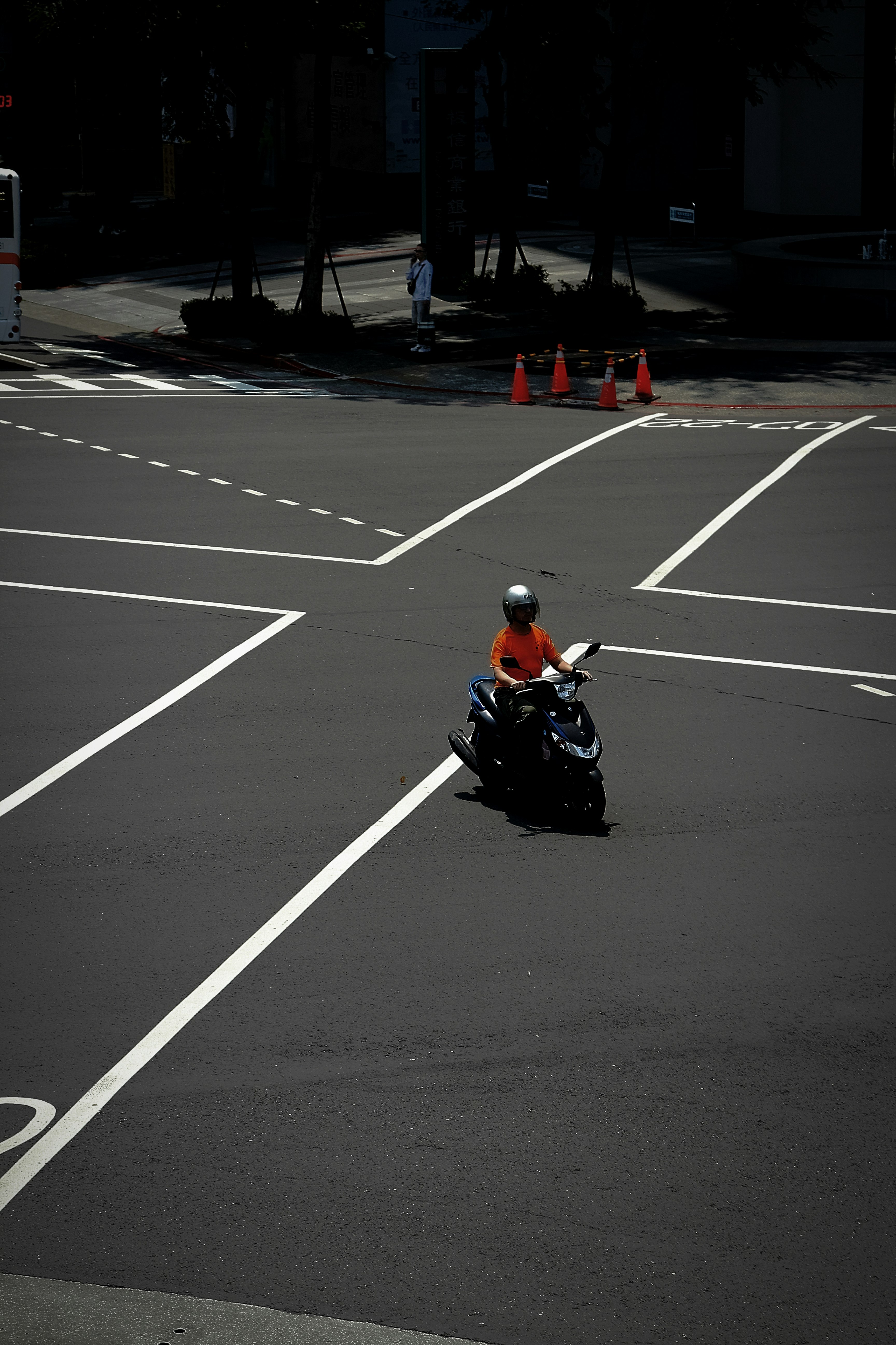交差点で信号待ちするバイクとオレンジコーンのある道路
