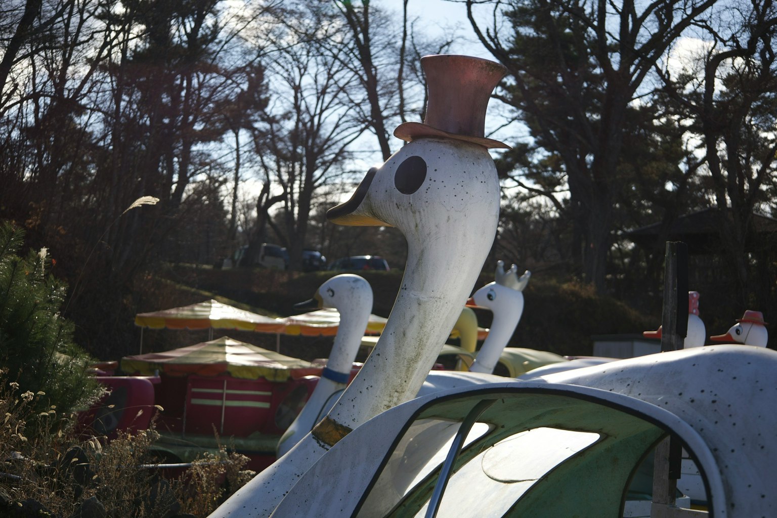 Une scène de parc avec une statue de cygne portant un chapeau haut de forme