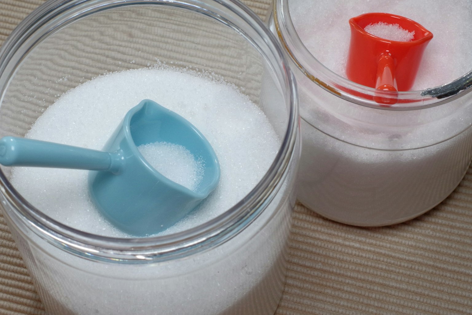 Hai hũ đường với một thìa màu xanh và một thìa màu đỏ