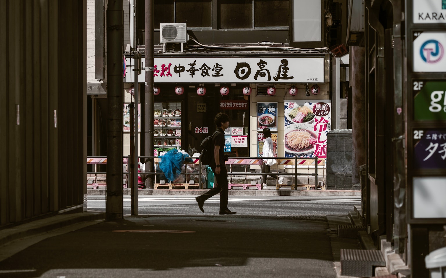 Une personne marchant dans une rue étroite avec un panneau de restaurant japonais