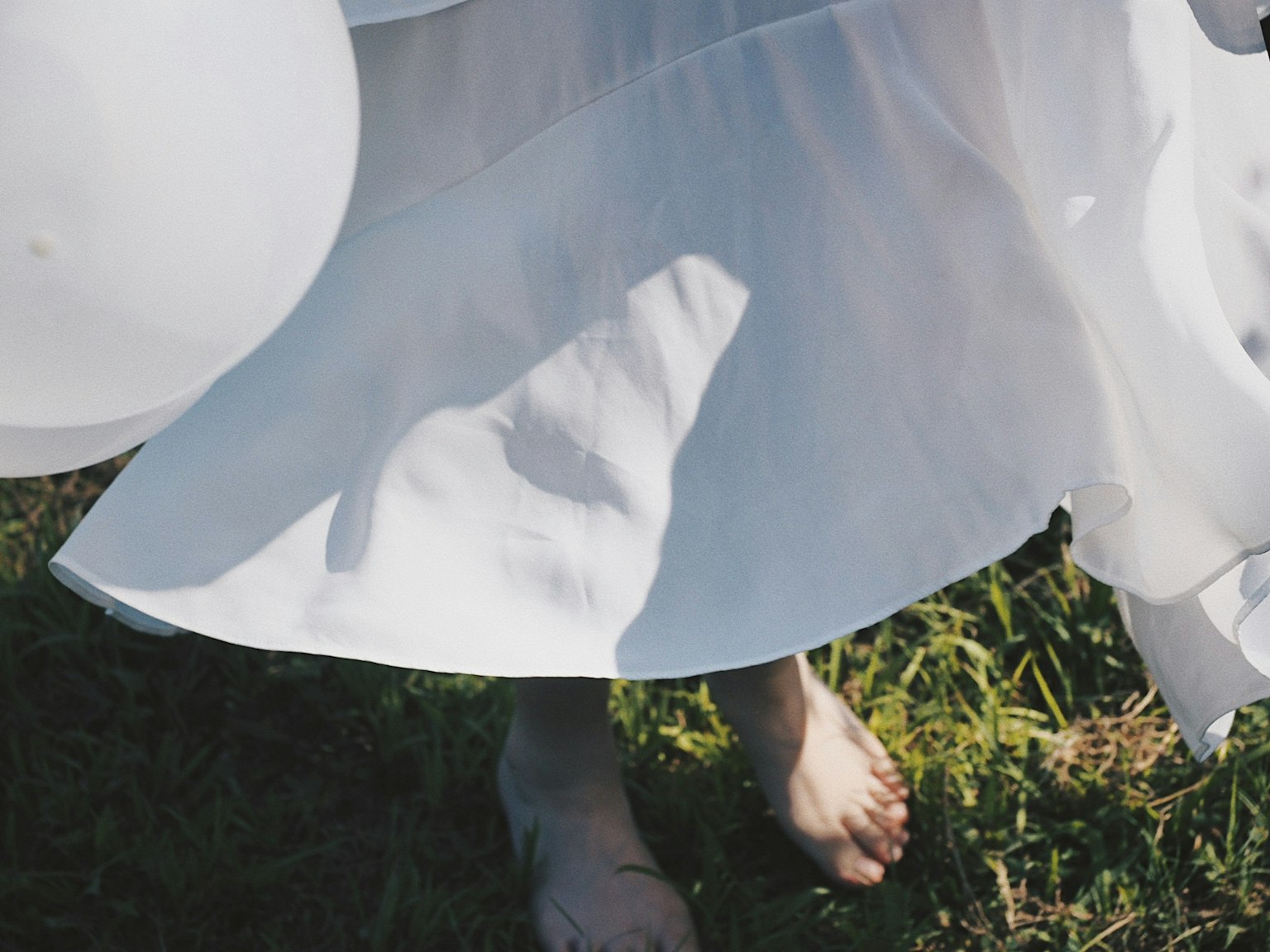 Una donna in abito bianco in piedi a piedi nudi sull'erba