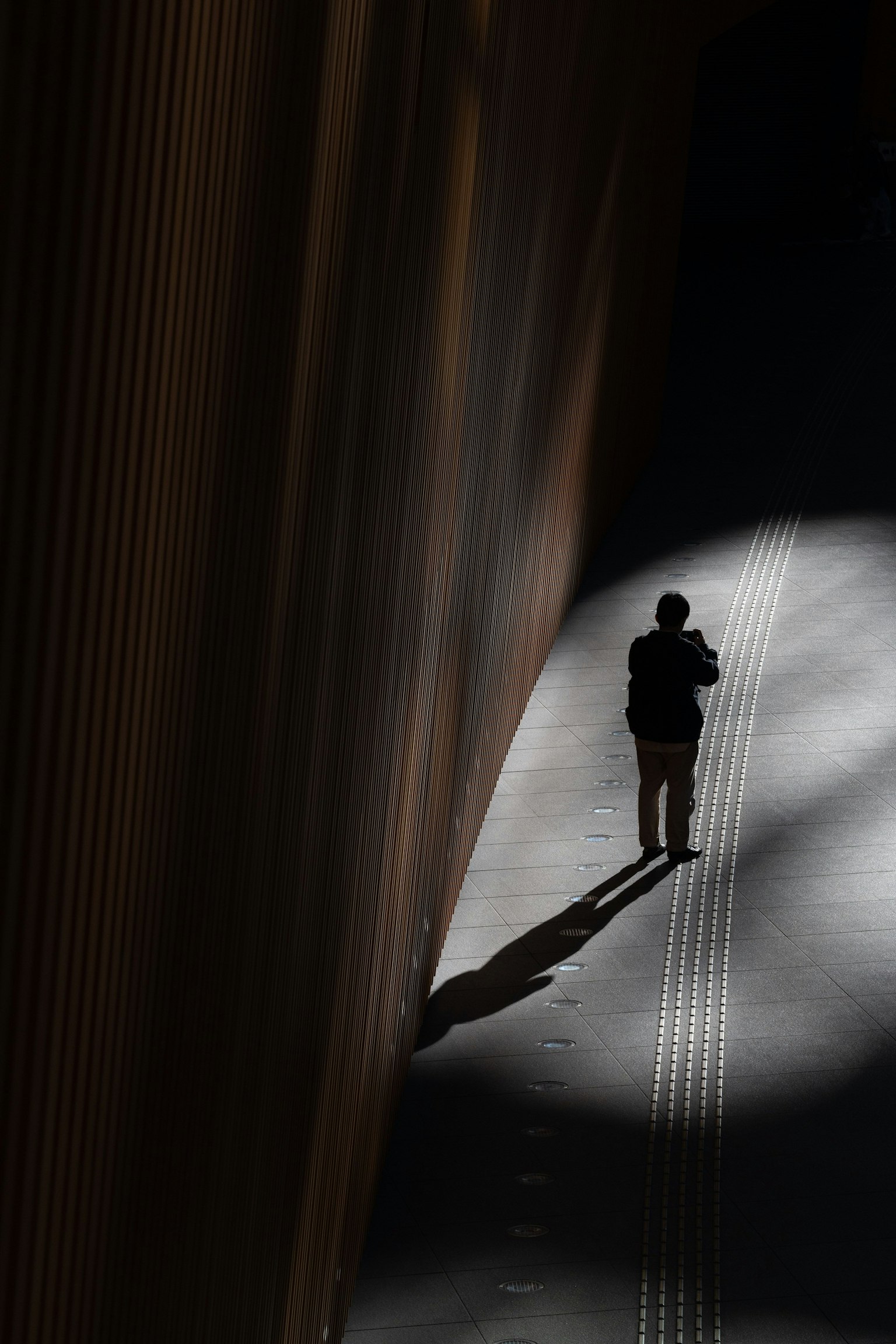 Silueta de una persona caminando en sombras con contraste de luz