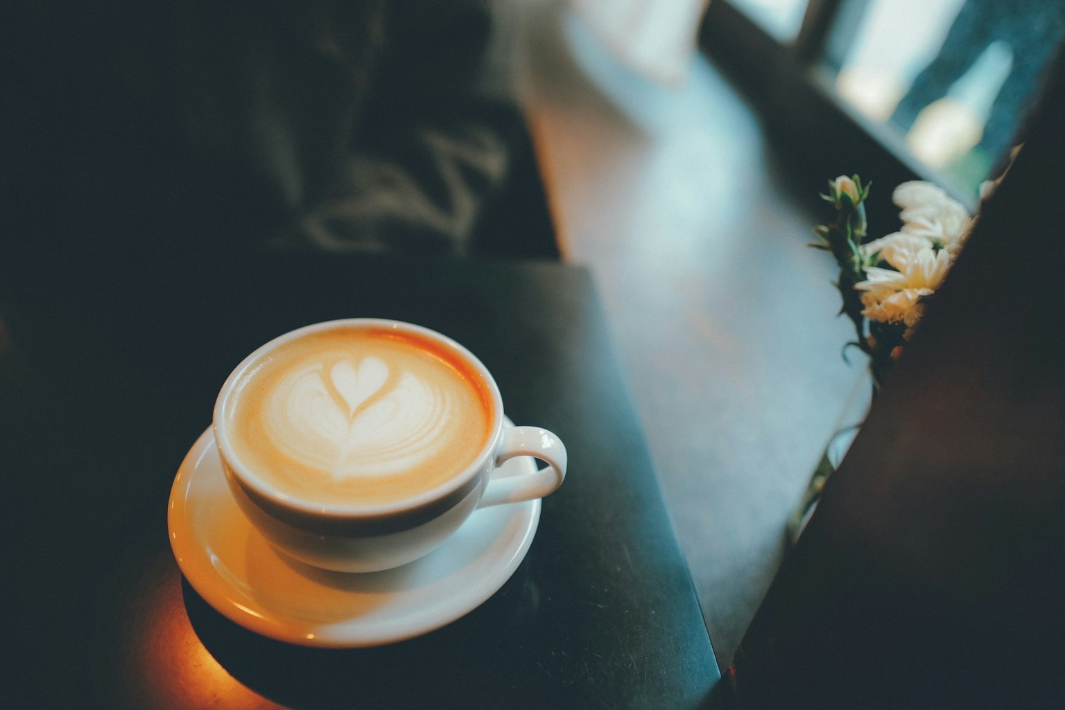 ถ้วยกาแฟที่มีลาเต้อาร์ตเป็นรูปหัวใจบนโต๊ะกาแฟ