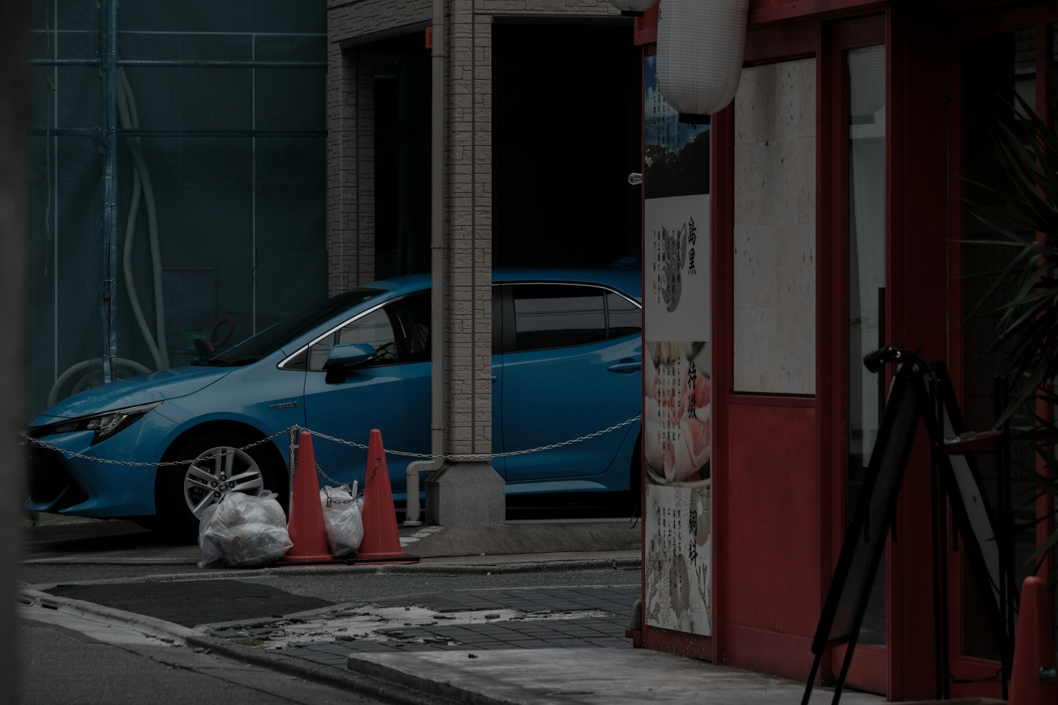 Urban scene featuring a blue car and red cones