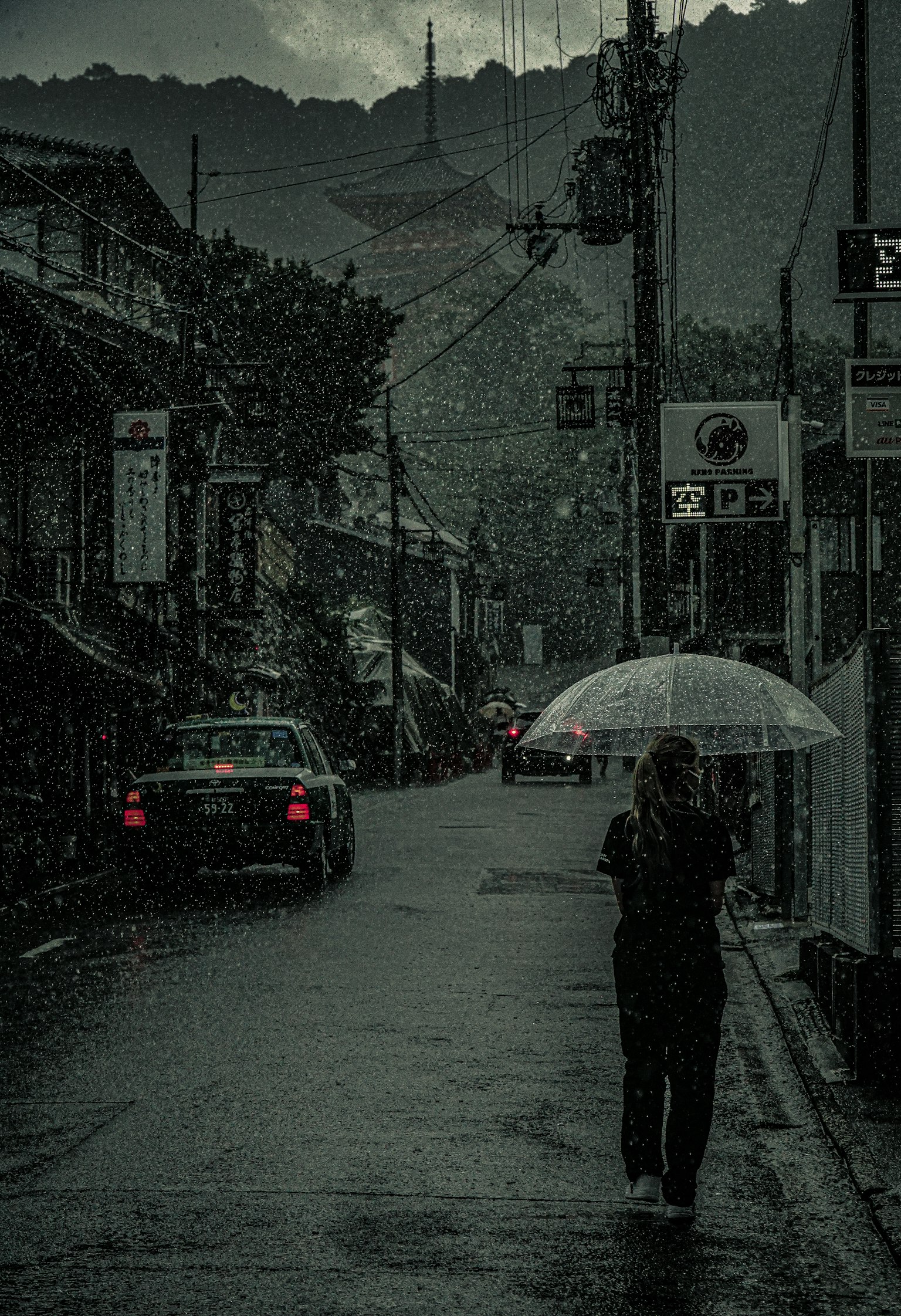 雨中撑伞行走的人和背景中的山