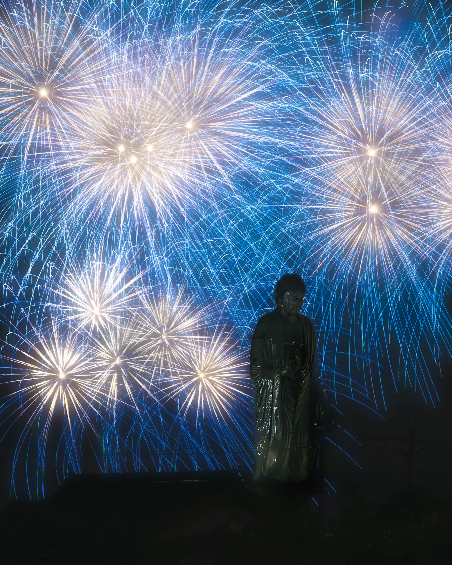 Silhouette d'une personne se tenant devant un fond de feux d'artifice bleus vibrants