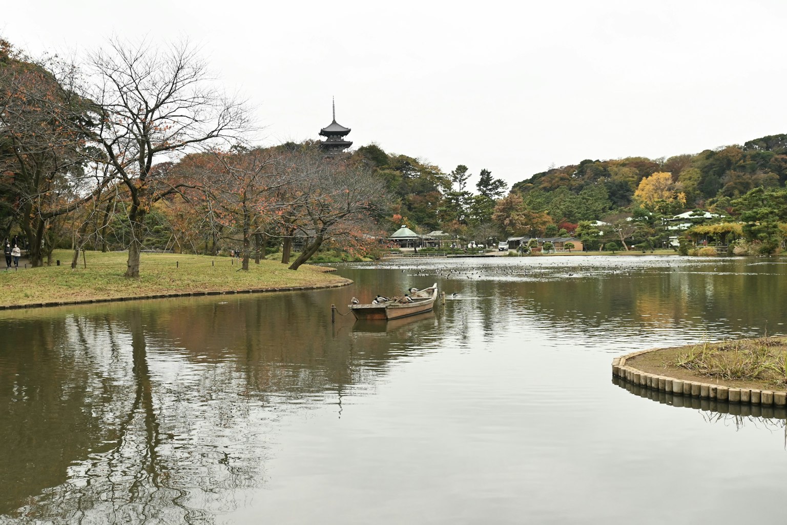 ภาพบ่อน้ำที่เงียบสงบพร้อมเรือเล็กและเจดีย์ในระยะไกล