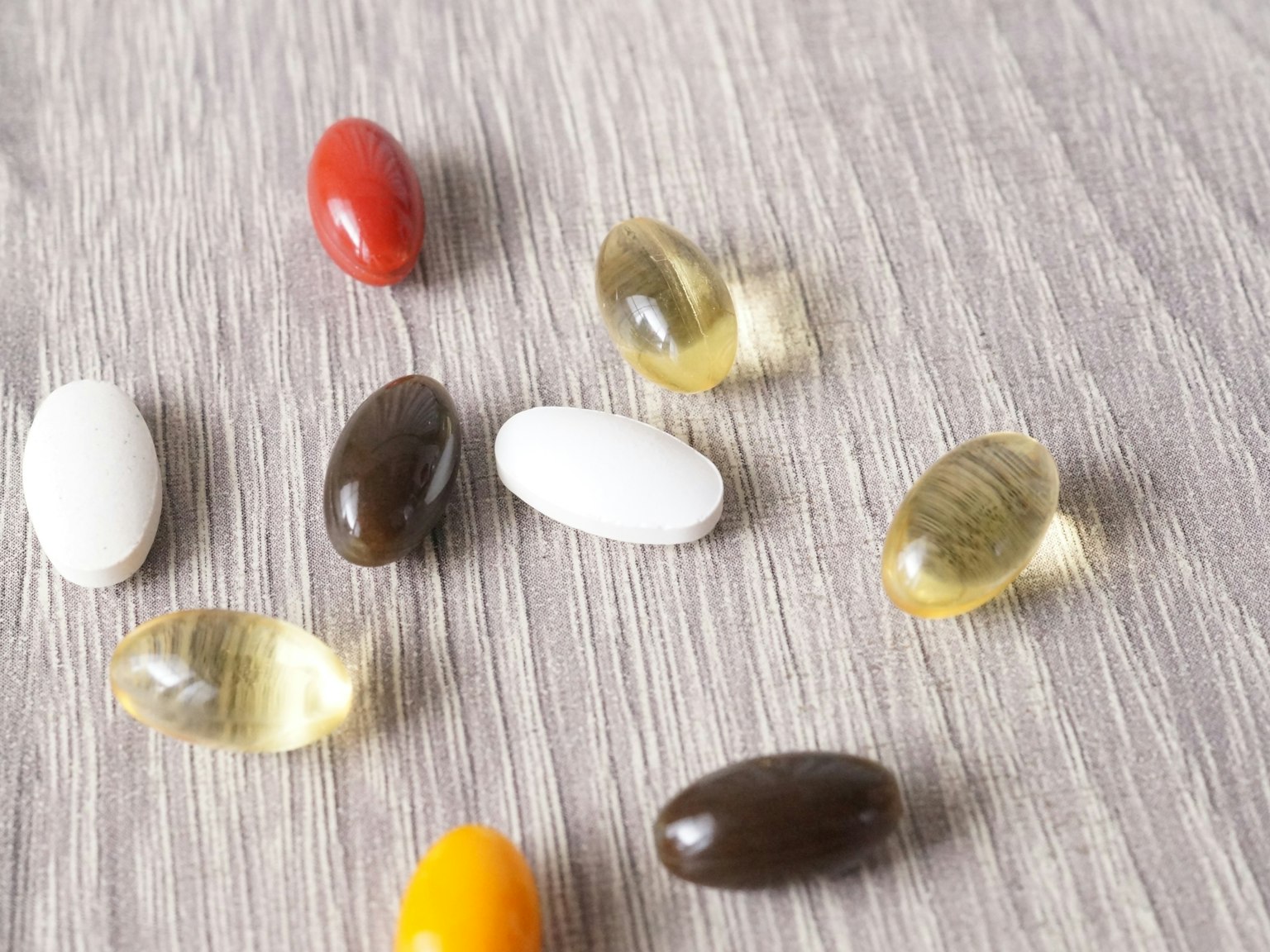 Capsule di integratori colorate sparse su una superficie in legno