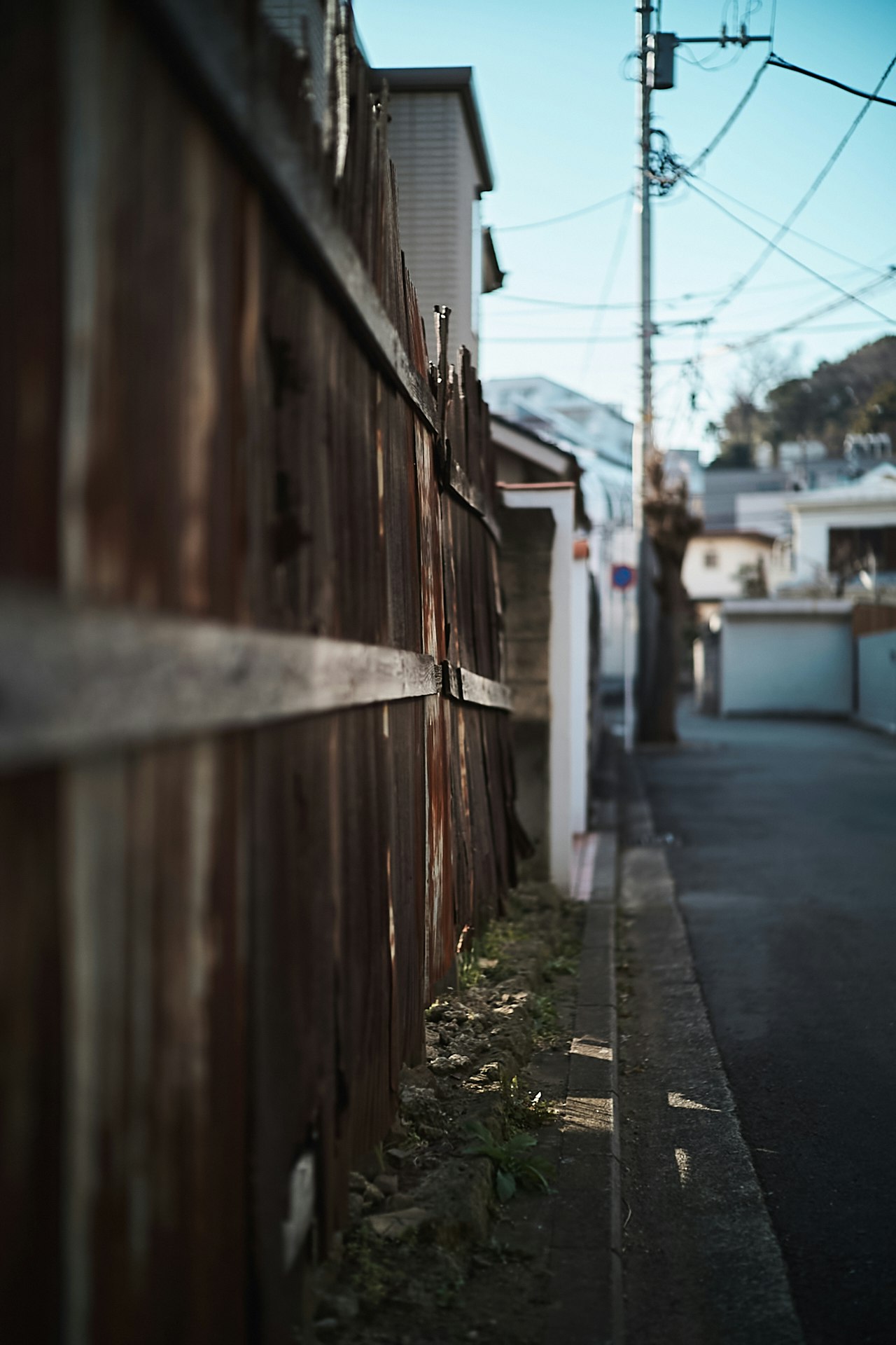 路地に並ぶ木製の壁と電線のある町並み
