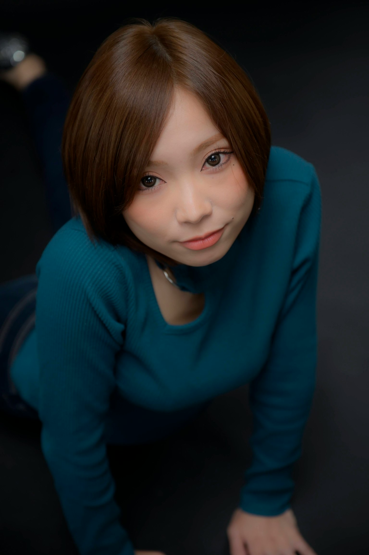 Woman in a blue top lying on a black background