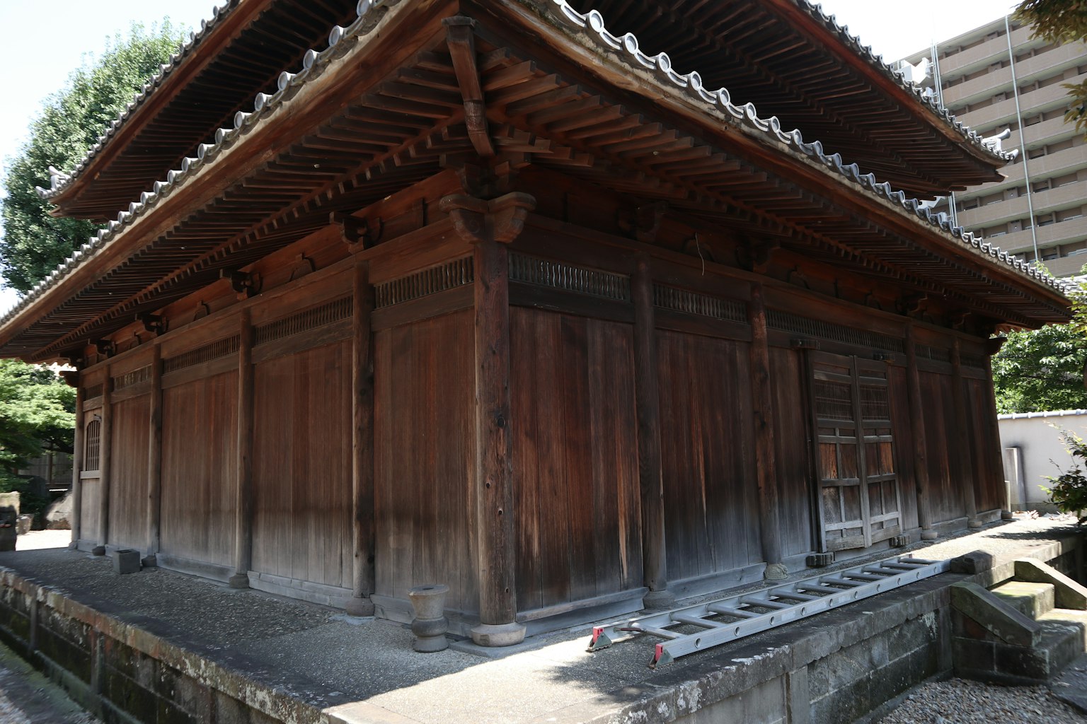 A photo showing an old wooden structure with modern buildings in the background