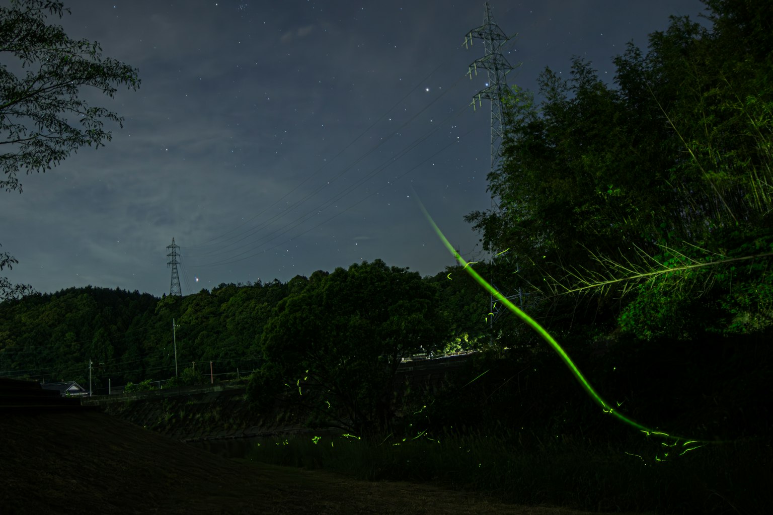 แสงสีเขียวตัดกับท้องฟ้ายามค่ำคืนและเงาภูเขา