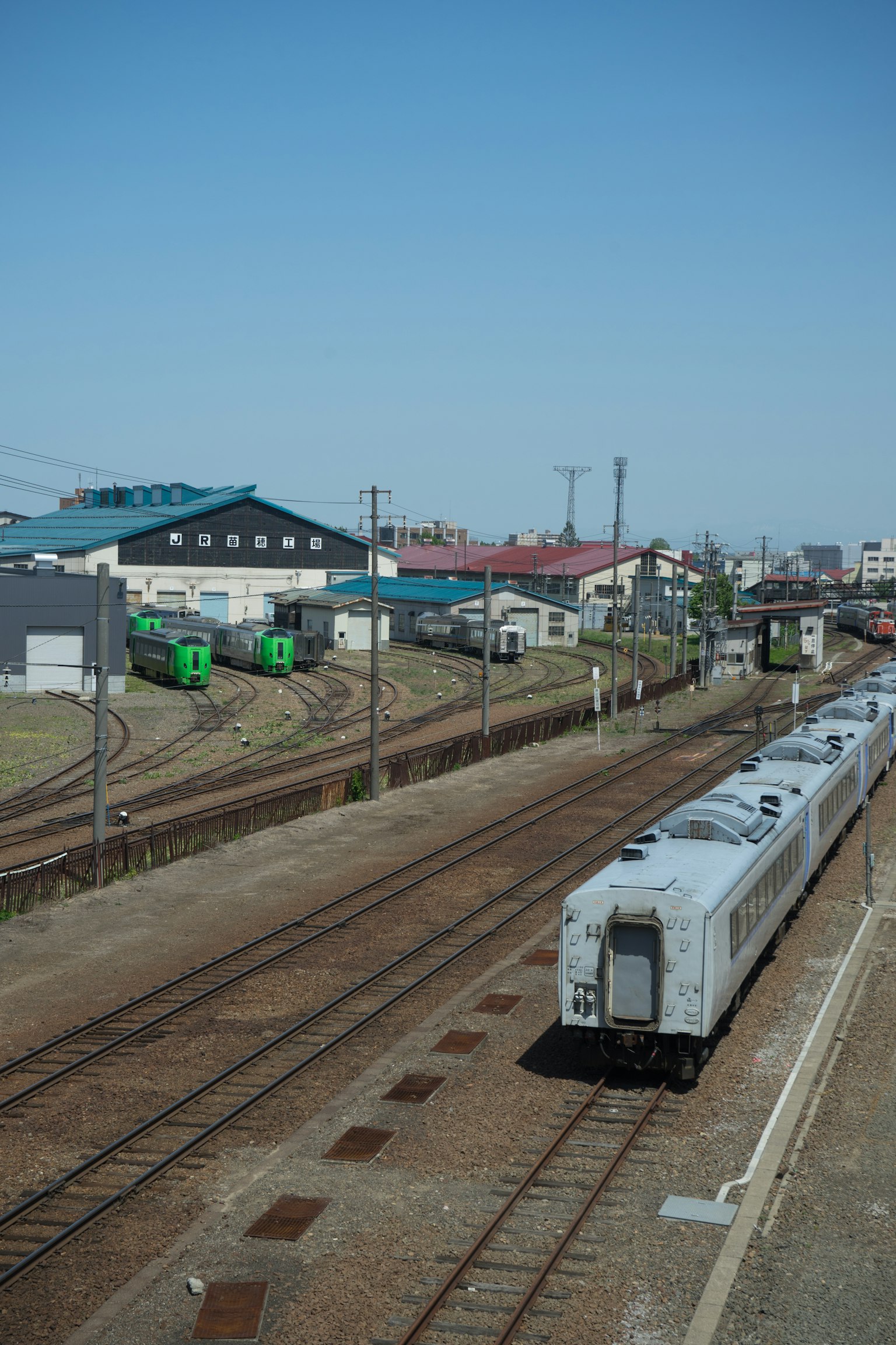 Railway tracks and train cars with a clear blue sky and buildings in the background