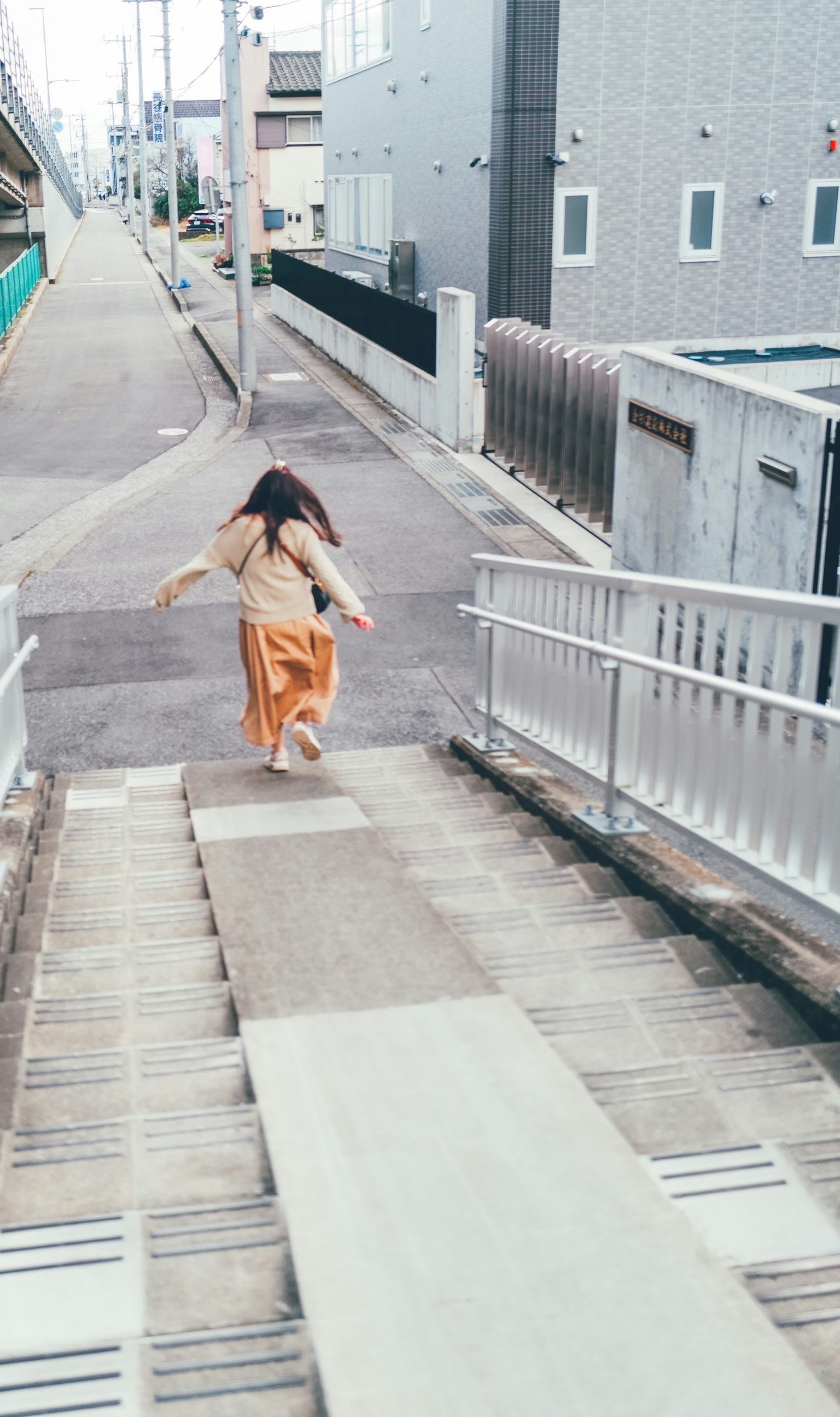 一位穿着飘逸服装的女性在城市环境中下楼梯