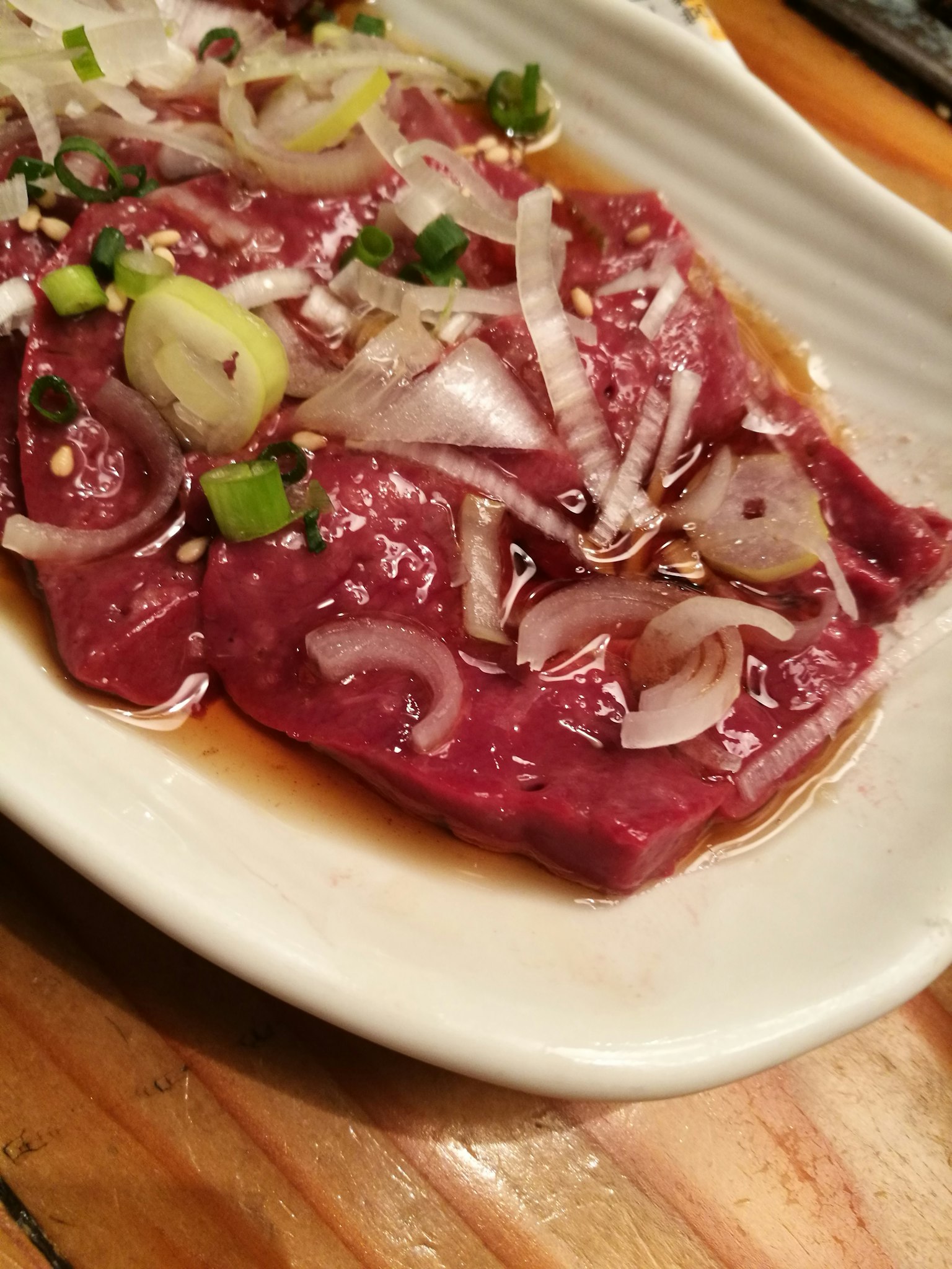 薄切肉片上放有青葱和洋葱的盘子