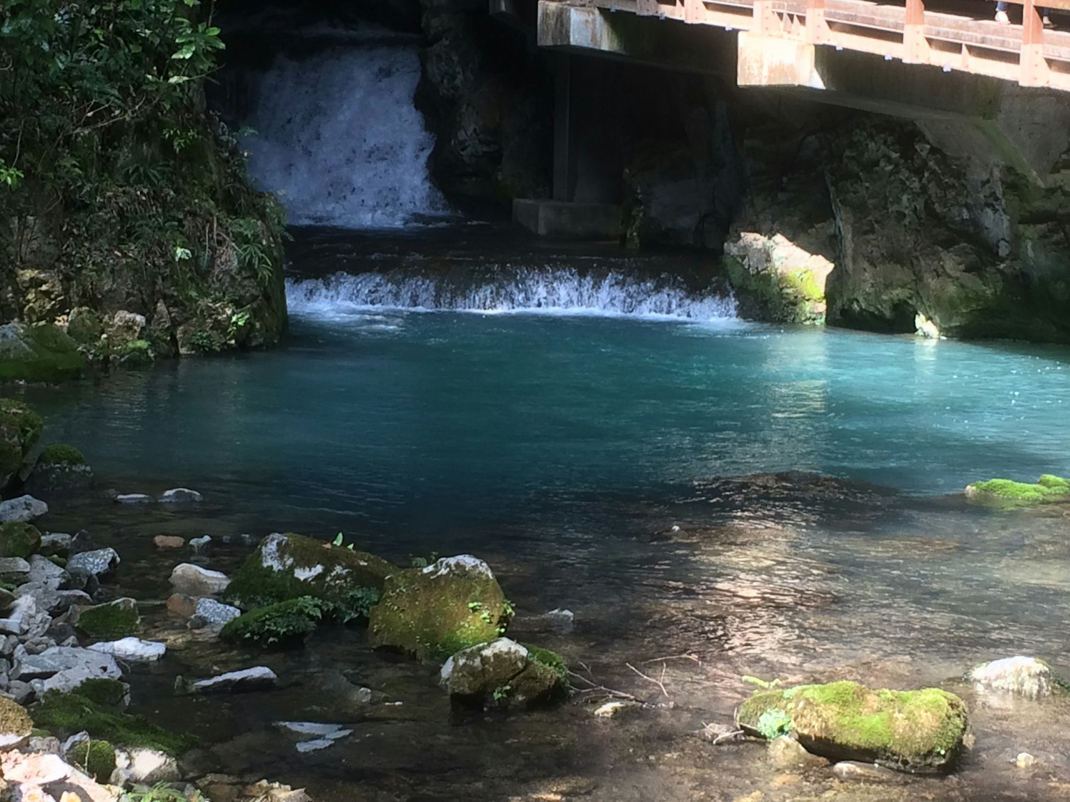Pemandangan alami dengan air terjun dan air biru jembatan di atasnya