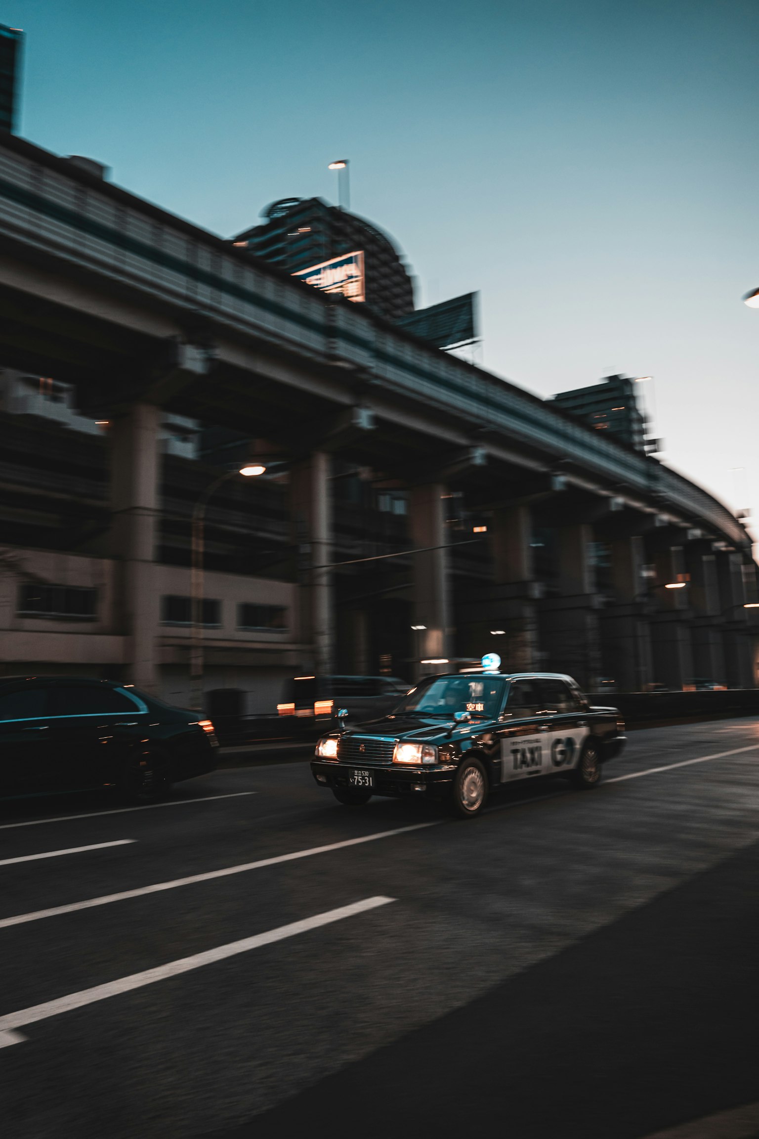 Taxi đang chạy dưới đường cao tốc với cảnh quan đô thị